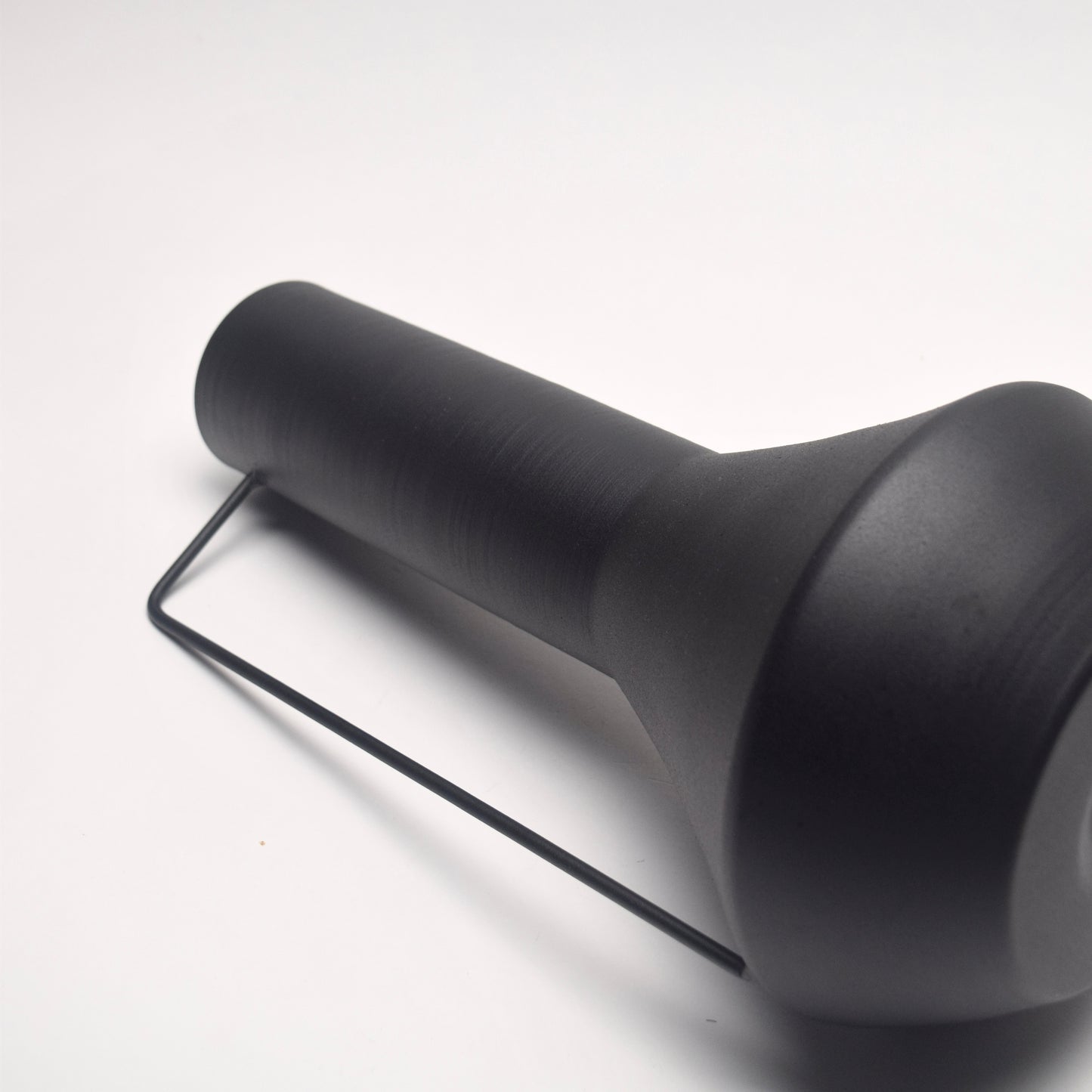 Tall matt black vase with a thin handle on its side