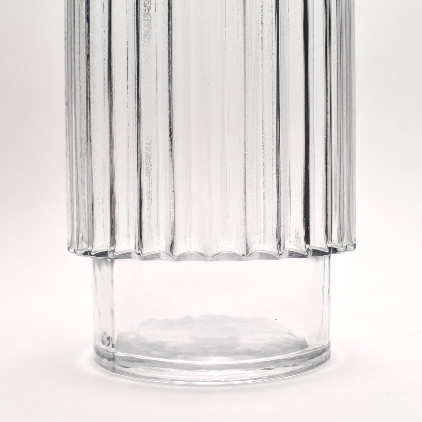 Close-up of clear glass vase with ribbed design and pedestal shape