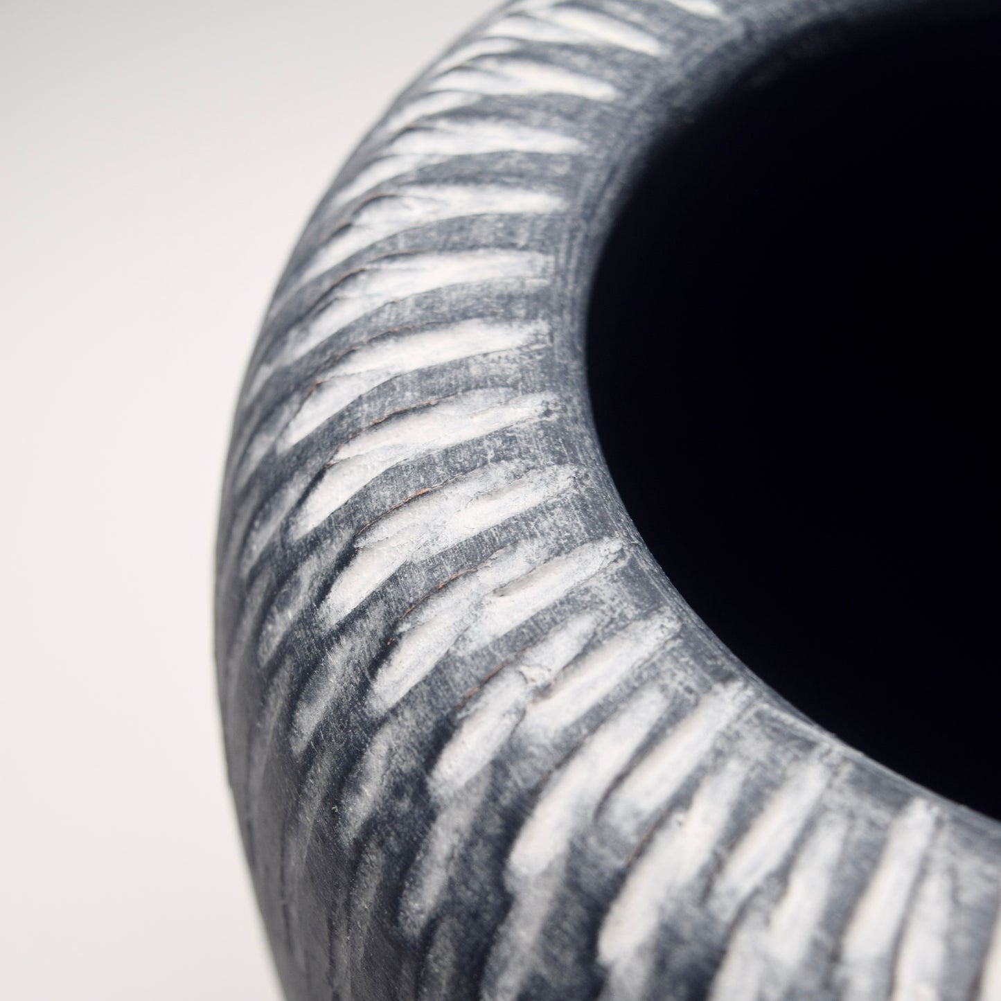 Close-up of a grey ceramic vase with a linear white pattern detail