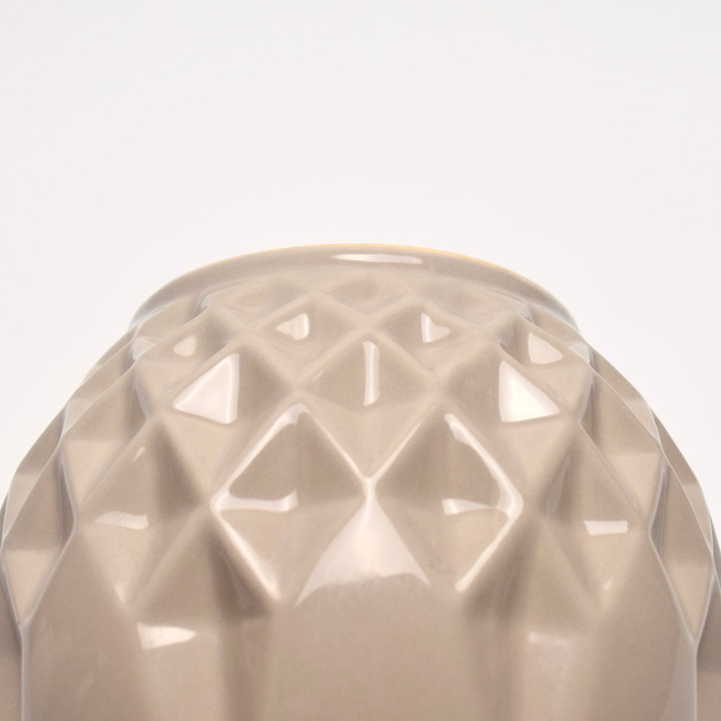 Close-up of a textured beige vase with geometric detailed pattern.