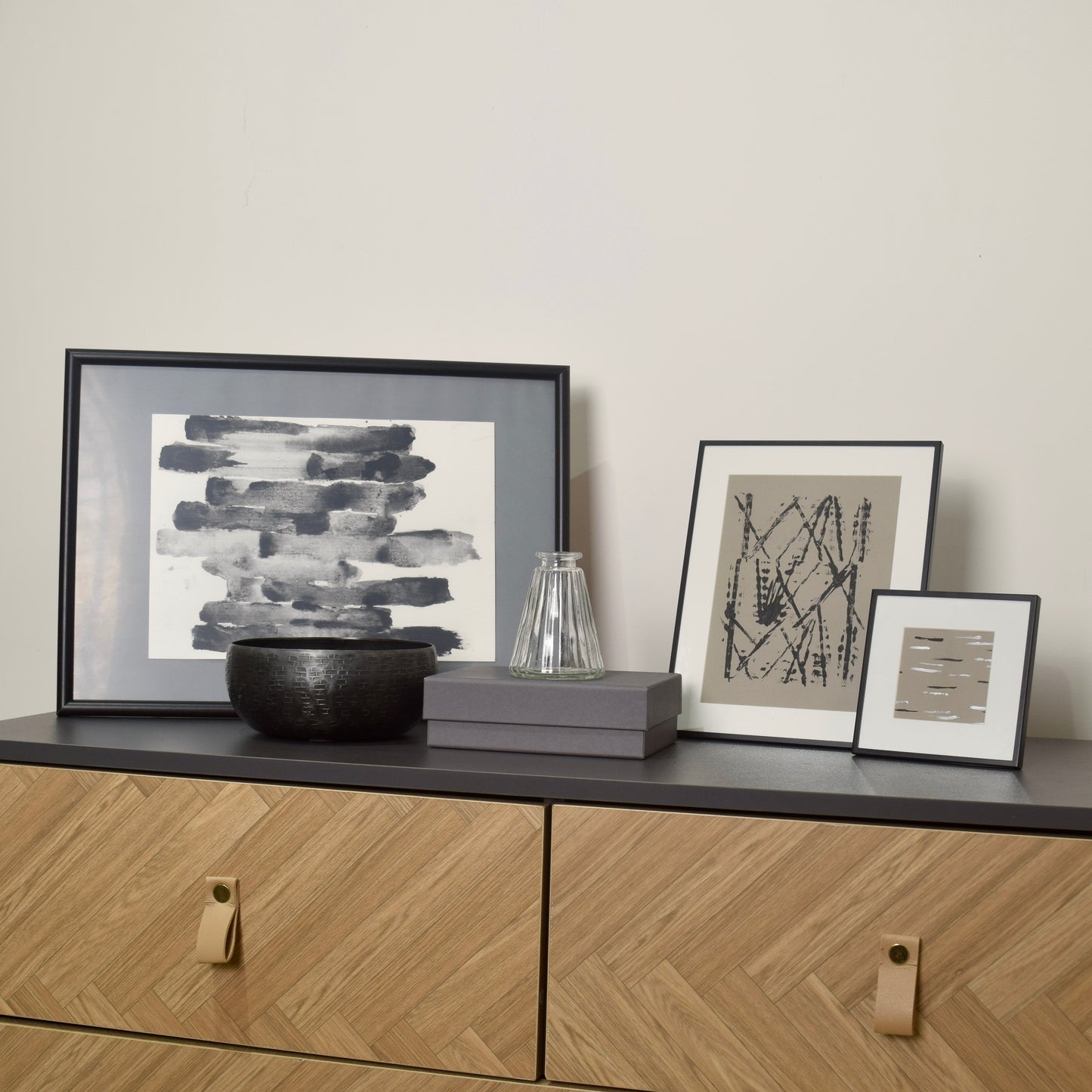Framed artworks and decorative items on a wooden cabinet for interior styling