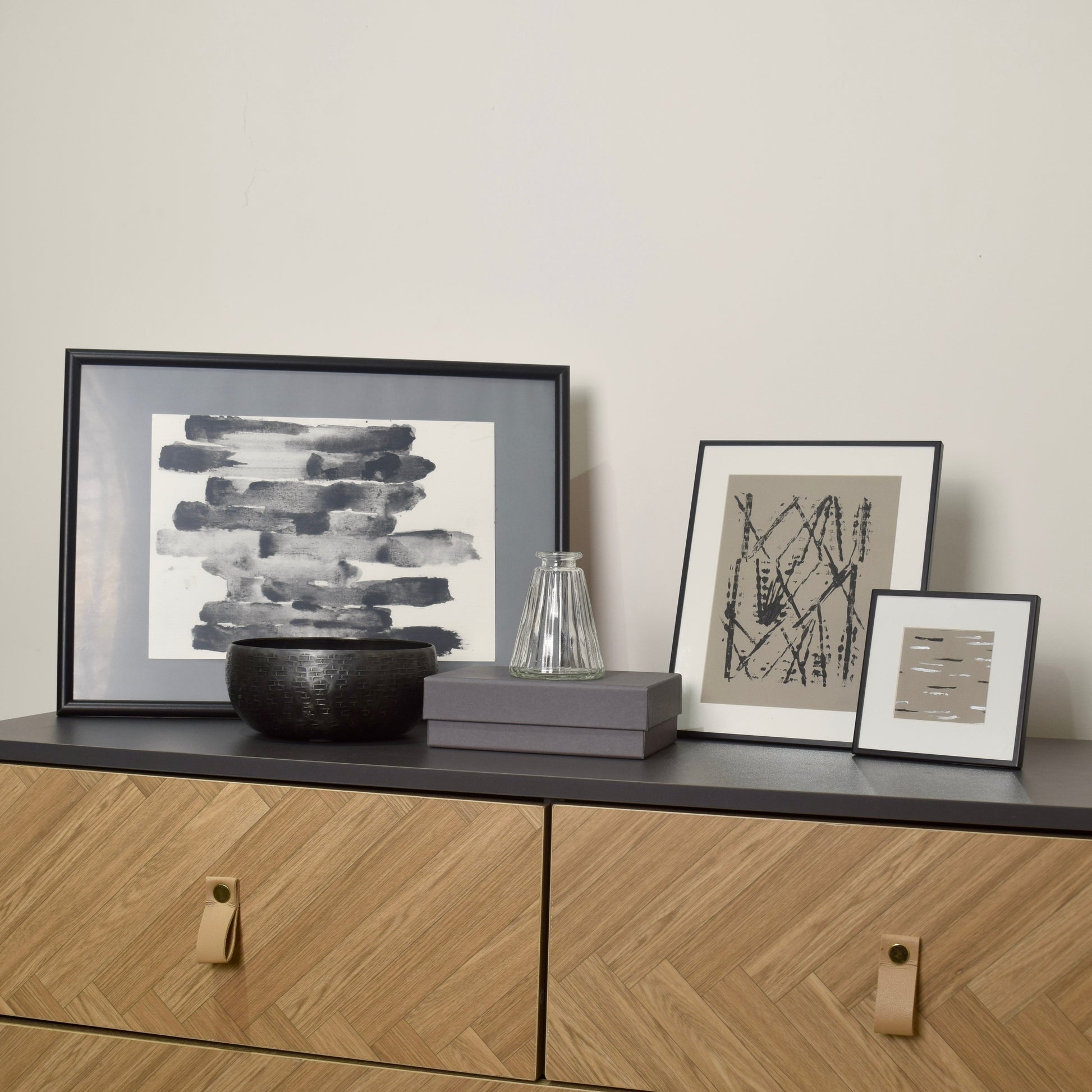 Framed artworks and decorative items on a wooden cabinet for interior styling