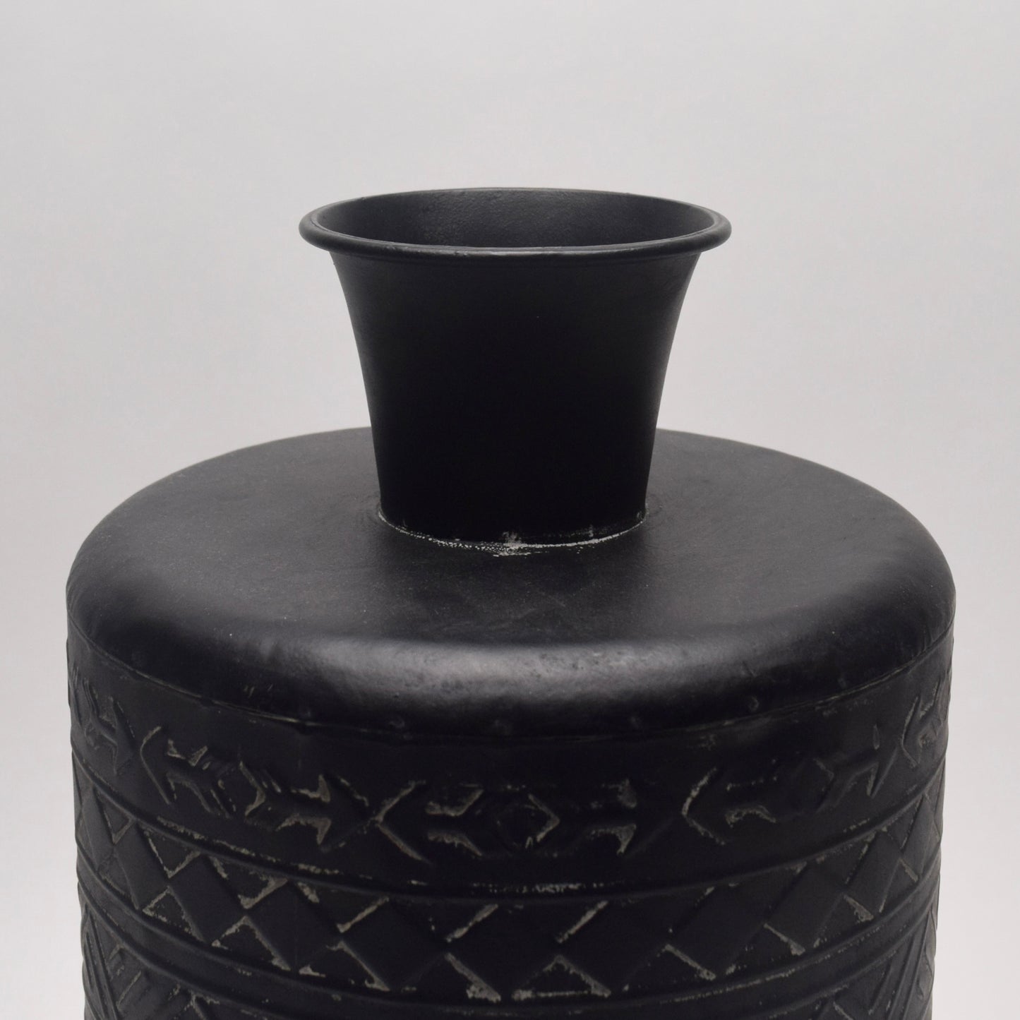 Close-up of the top of black metal vase with geometric patterns 