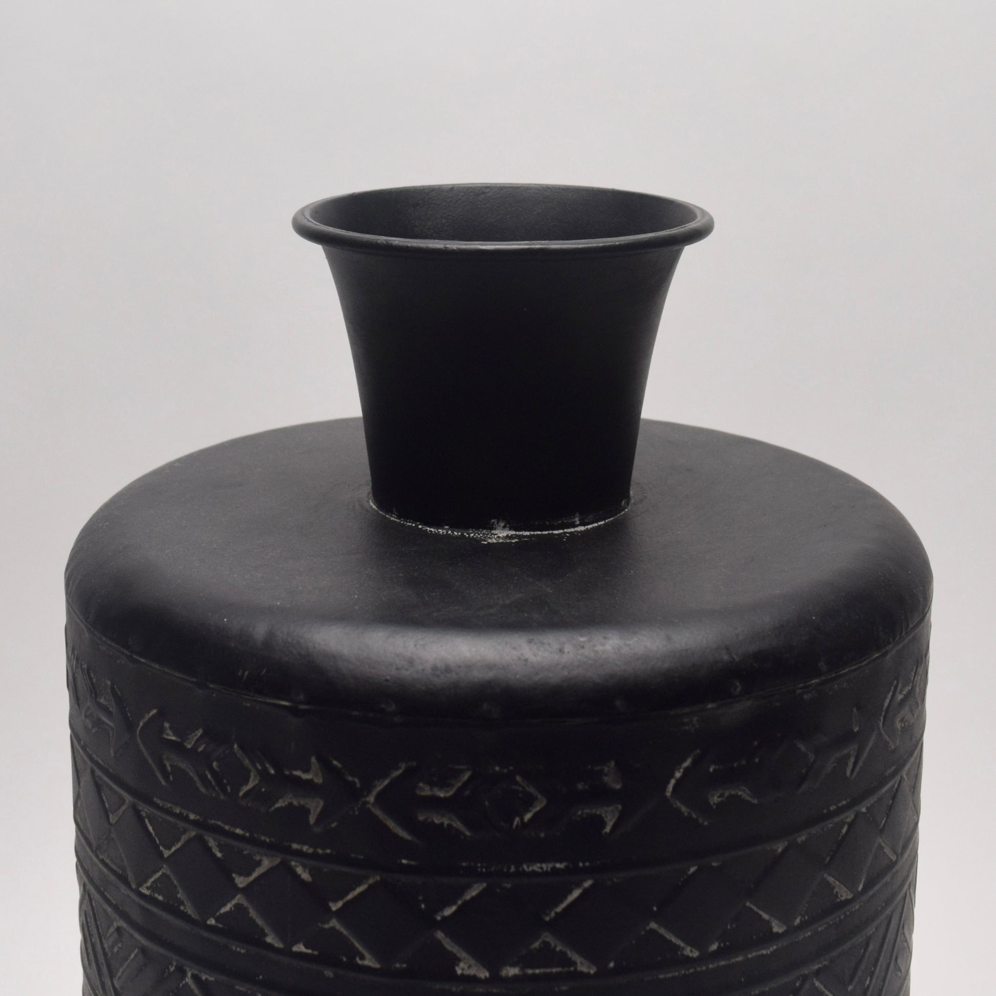 Close-up of the top of black metal vase with geometric patterns 