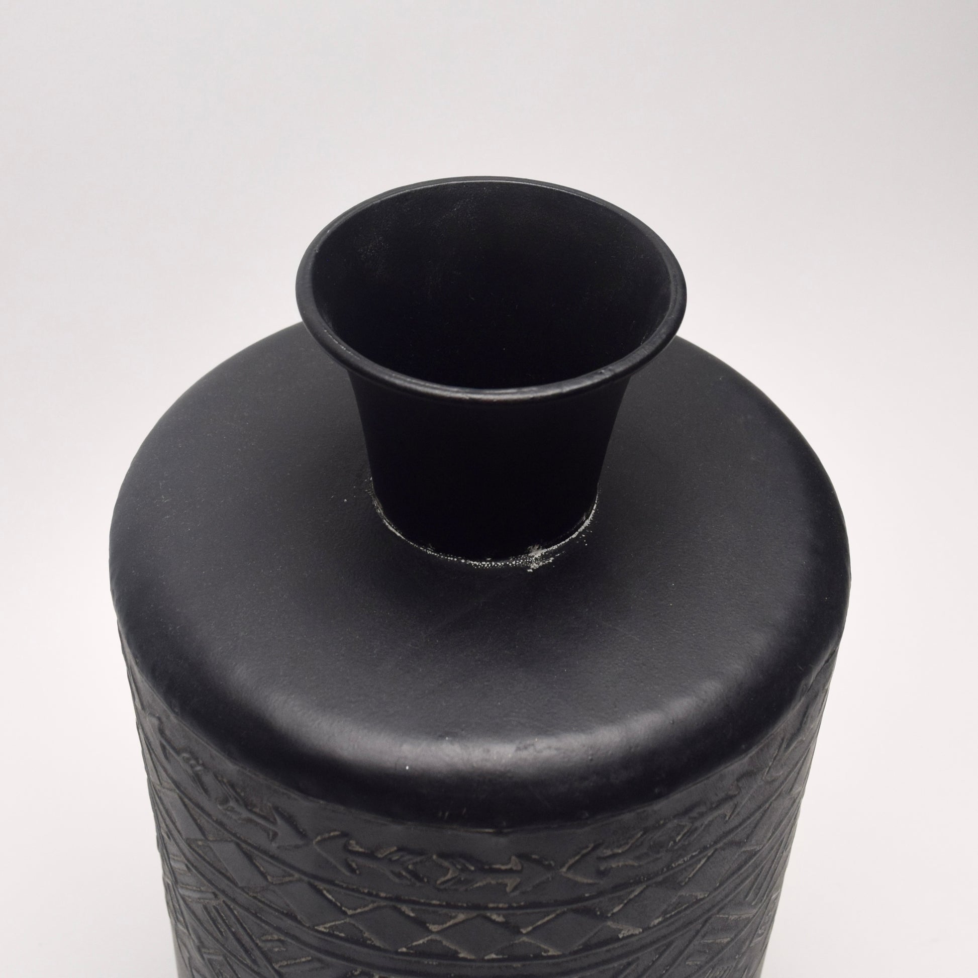 Black metal cylindrical vase with view of its circular neck 