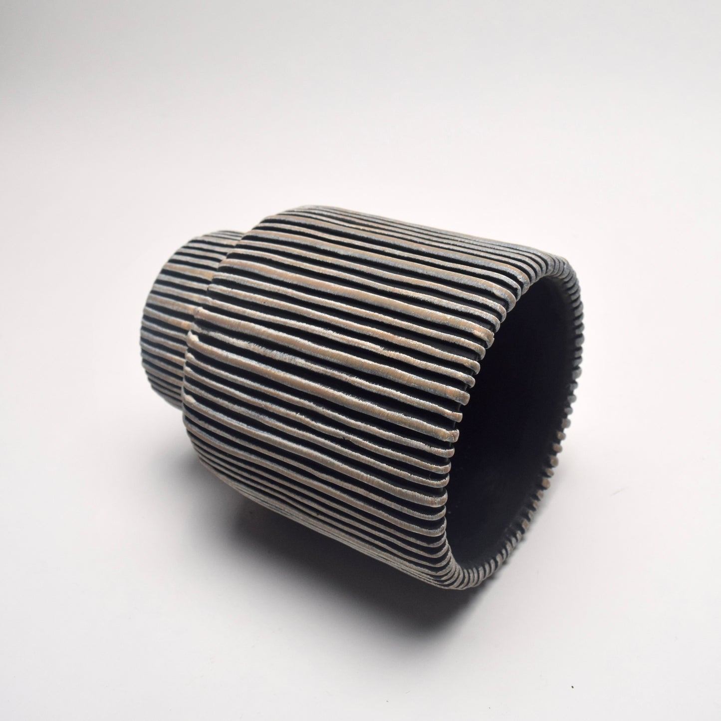 Cylindrical ceramic plant pot with ribbed texture and black and neutral vertical stripes on its side