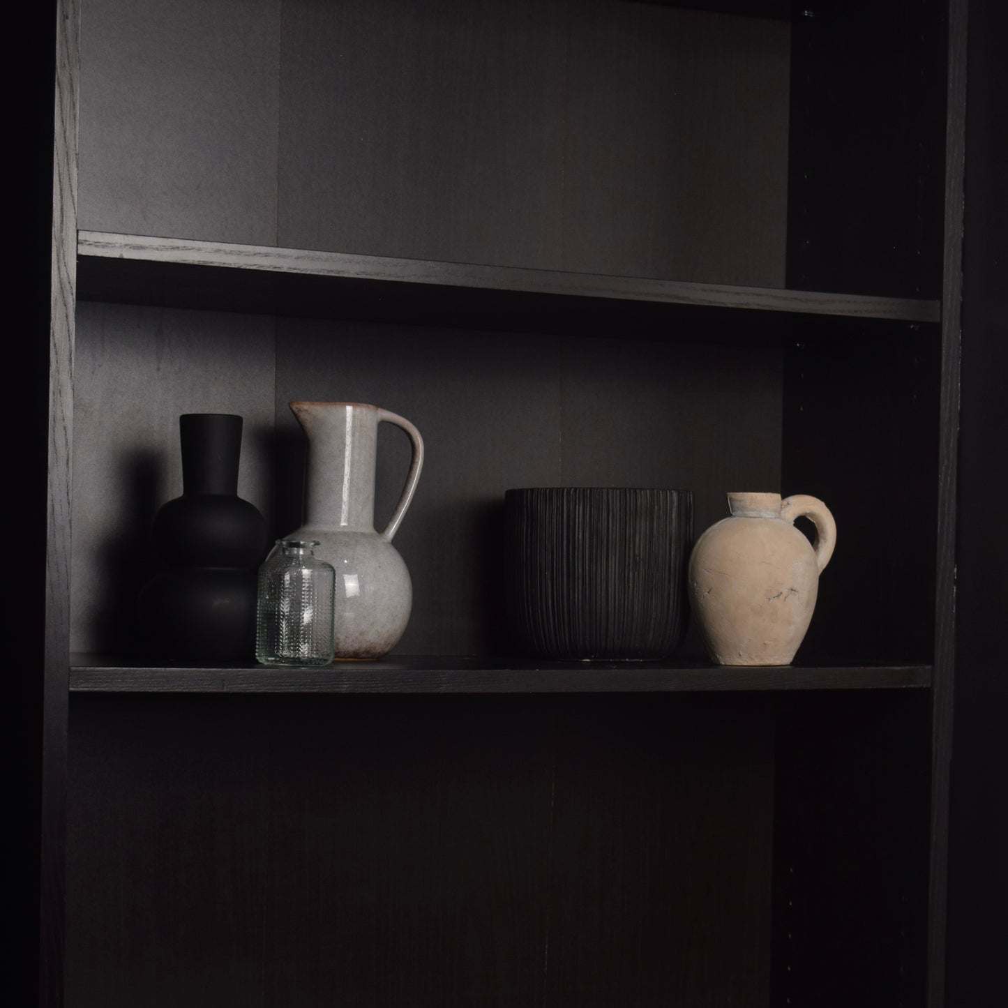 Five neutral vases on a black bookcase for modern shelf styling