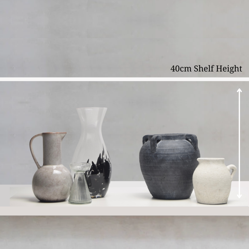 Five different ceramic and glass vases and pots on a shelf with a grey wall background