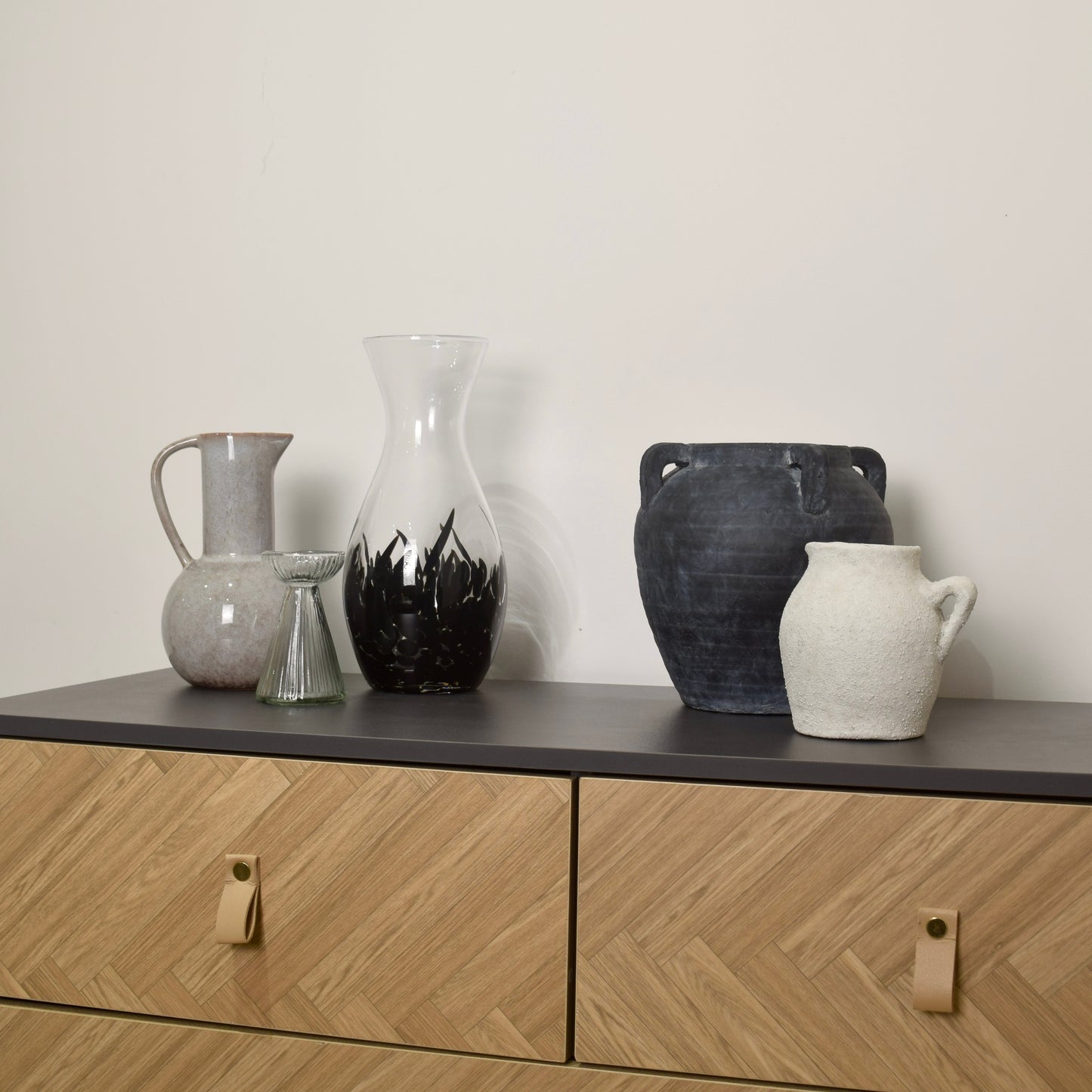 Set of ceramic vases on a wooden cabinet with a plain background for interior styling