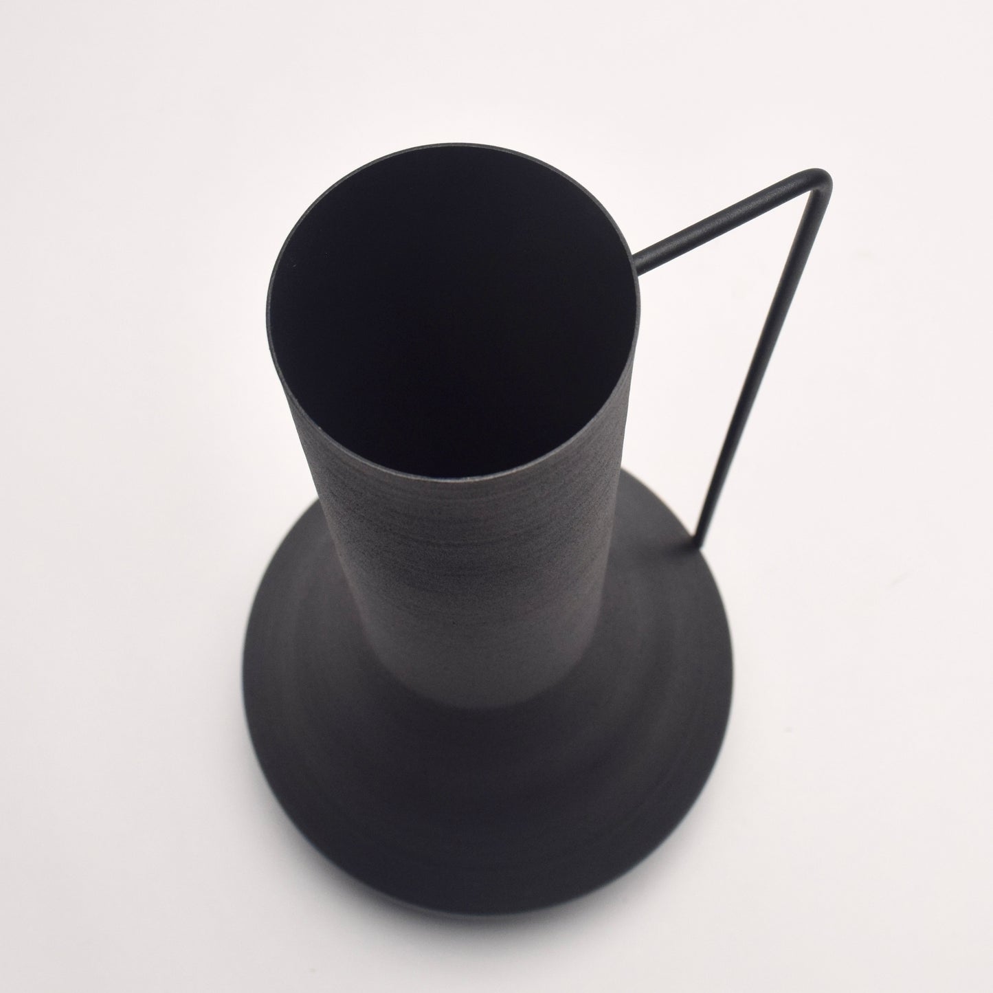 Top view of a tall matt black vase with a thin, delicate handle