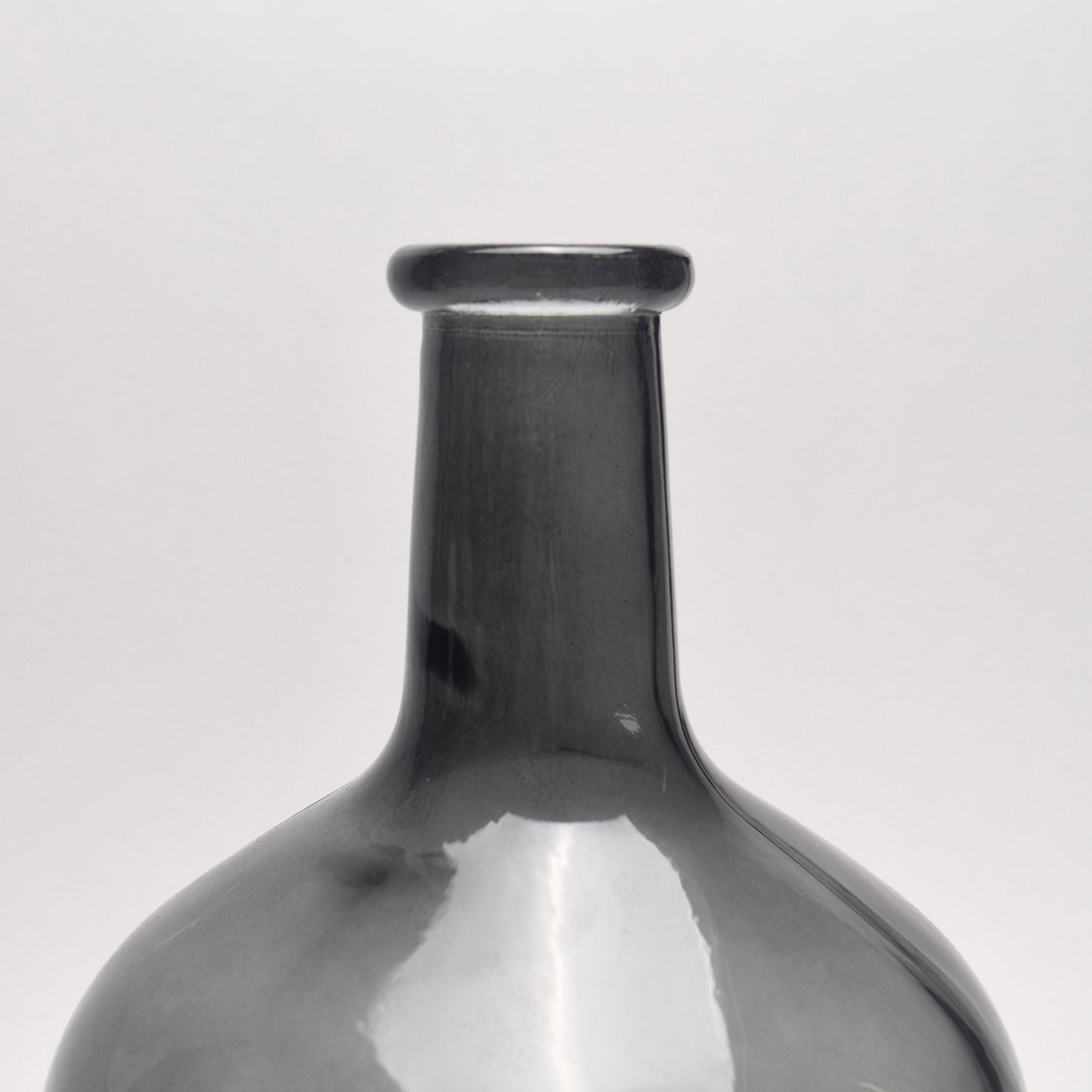 Close-up of top of charcoal glass bottle vase