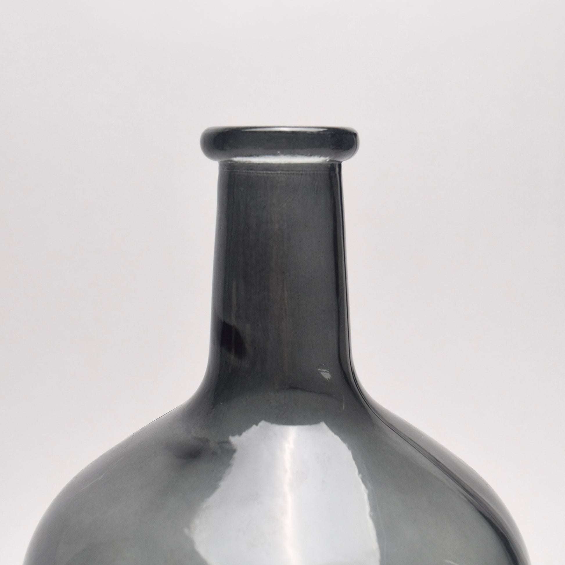 Close-up of top of charcoal glass bottle vase