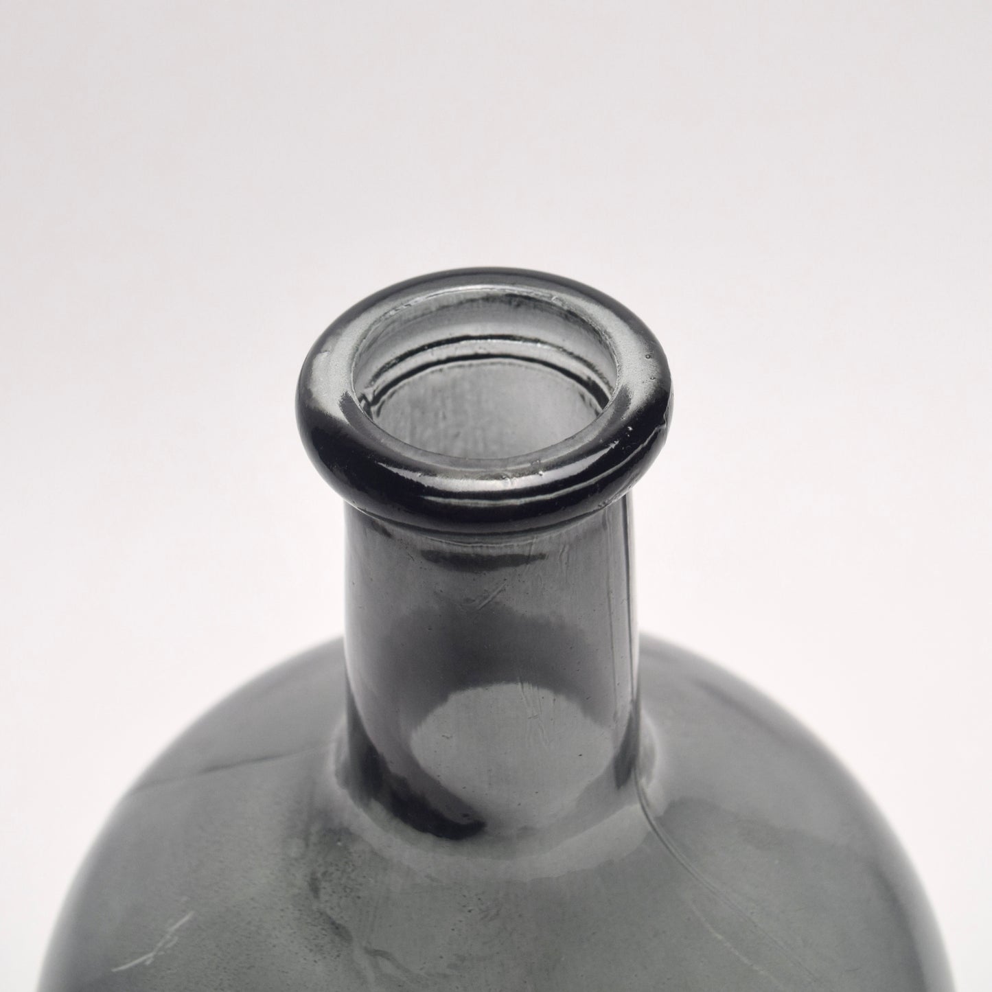 Close-up of a charcoal glass bottle neck on a white background