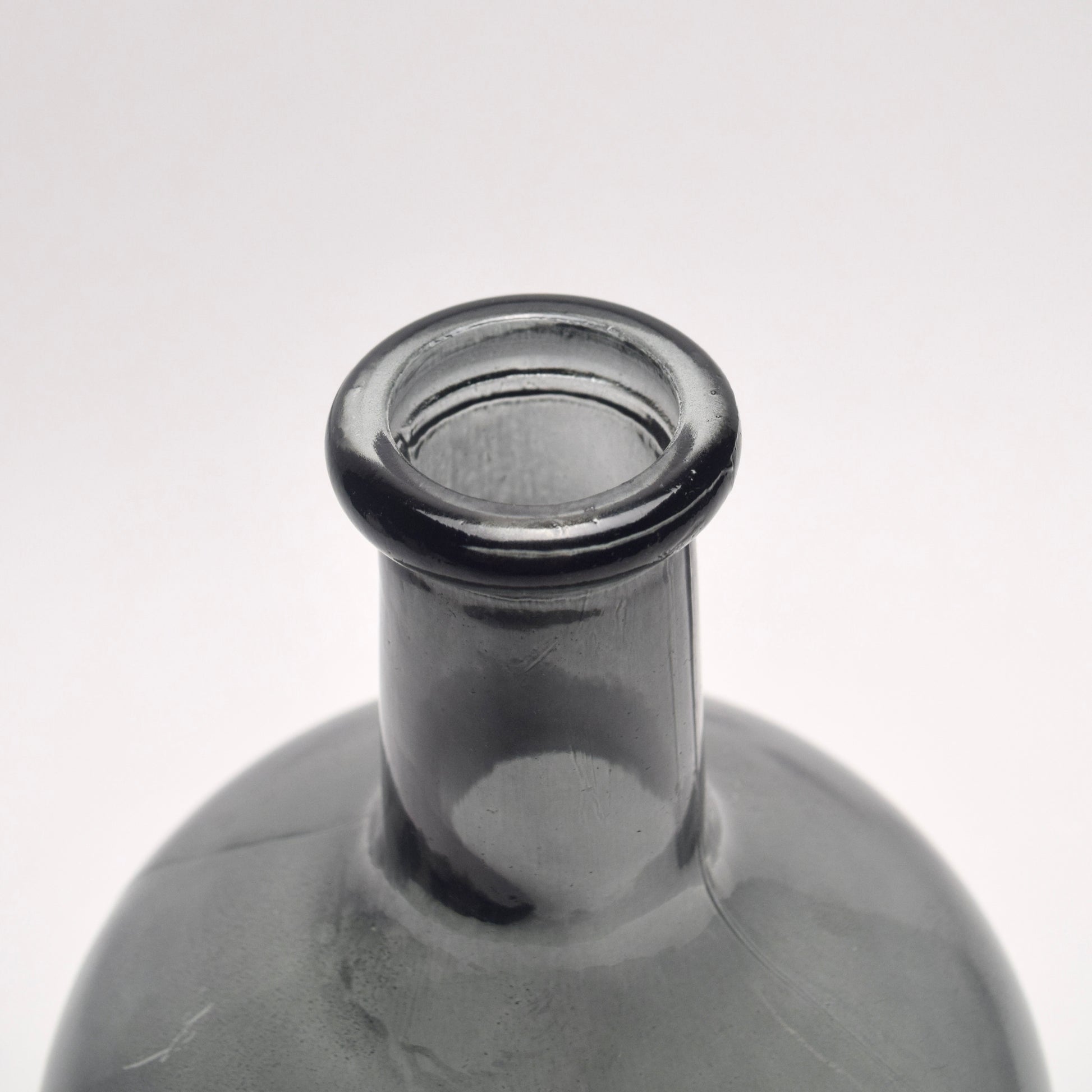 Close-up of a charcoal glass bottle neck on a white background