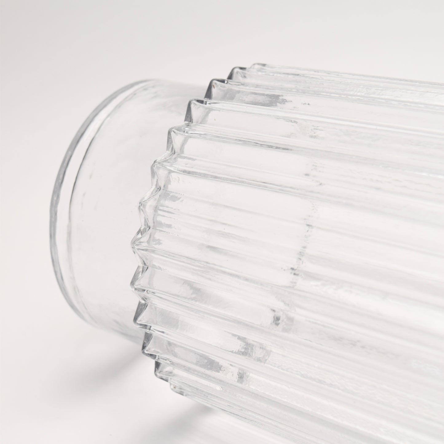 Close-up of a clear glass vase with ribbed design and pedestal bottom detail