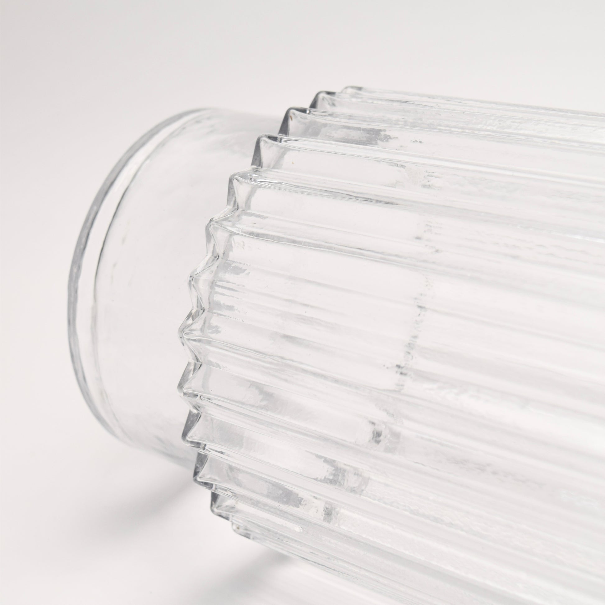 Close-up of a clear glass vase with ribbed design and pedestal bottom detail