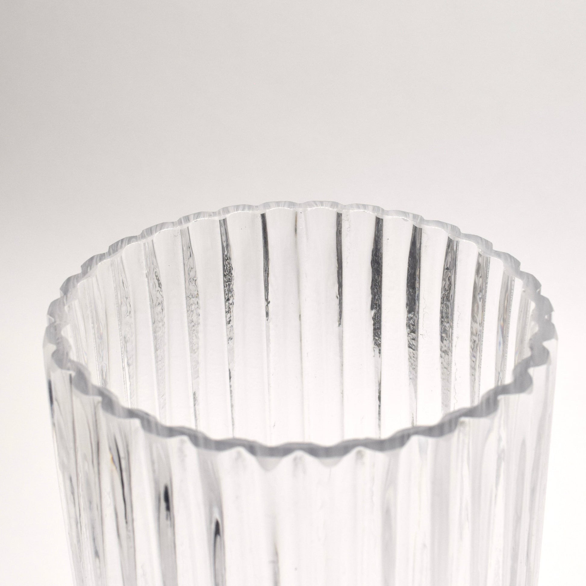 Top detail of a cylindrical clear glass vase with ribbed design 