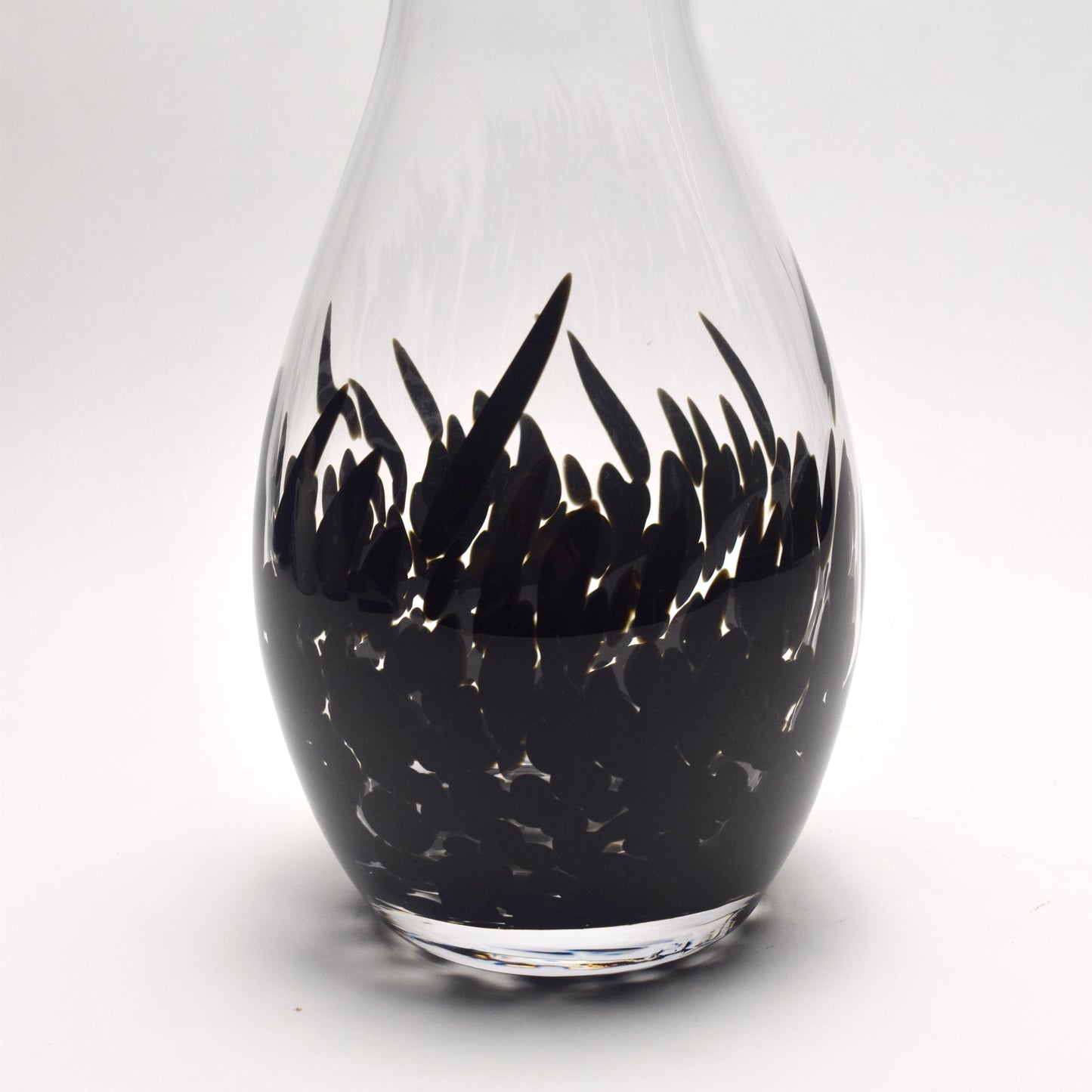 Bottom section of a clear glass vase with a decorative abstract pattern