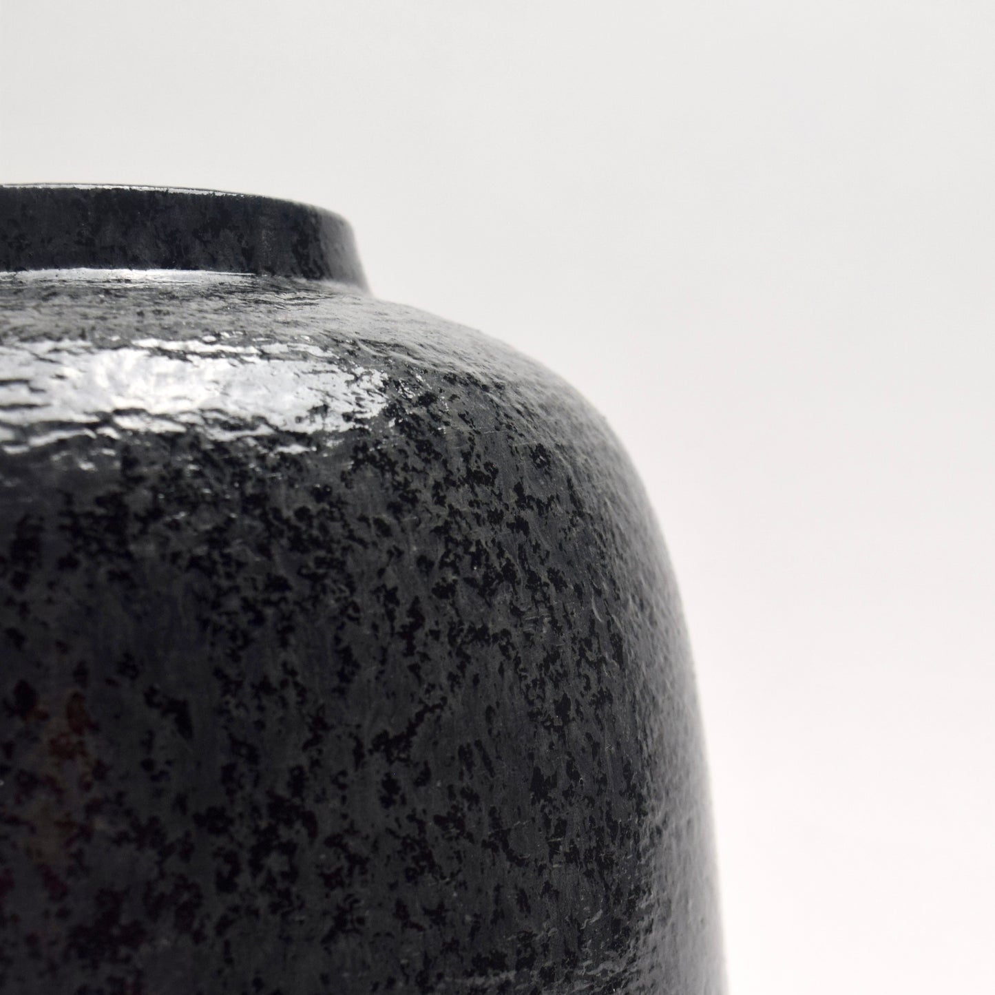 Close-up of a black speckled ceramic vase 