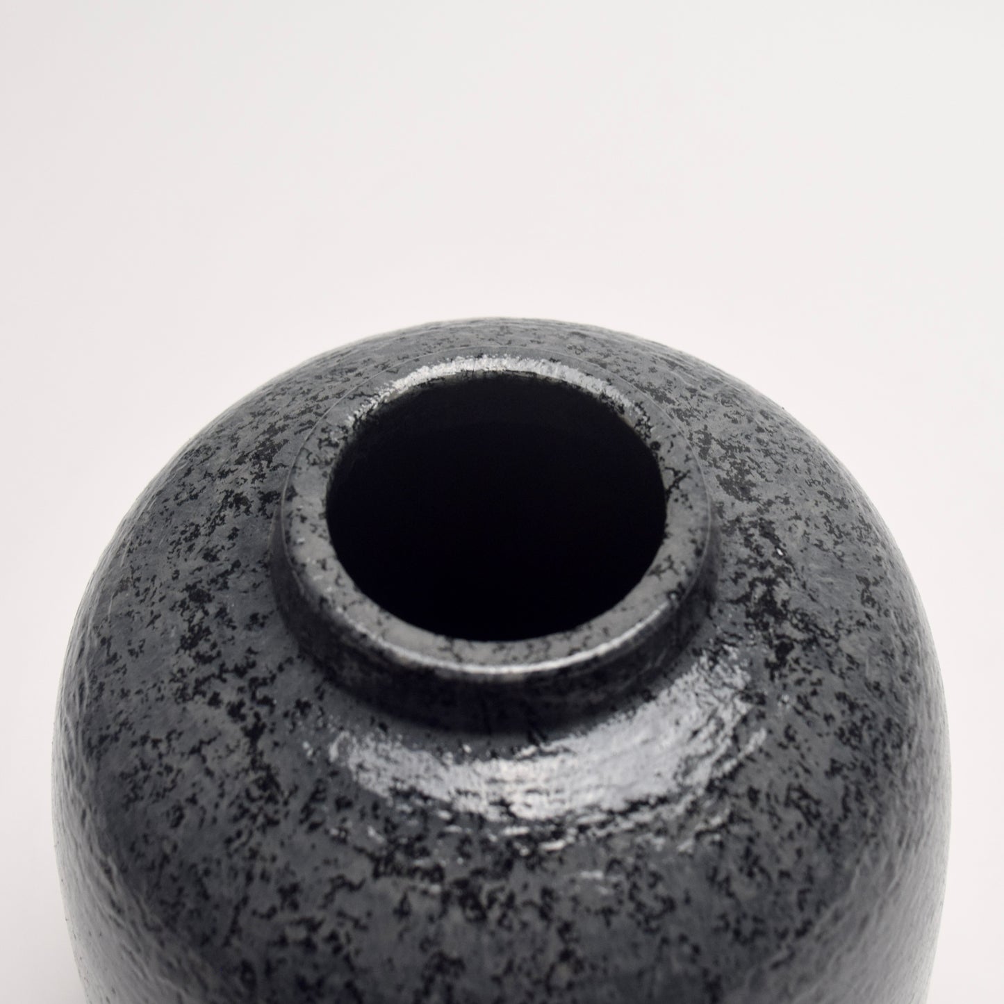 Dark grey, charcoal terracotta vase with mottled surface pattern top circular shape close-up