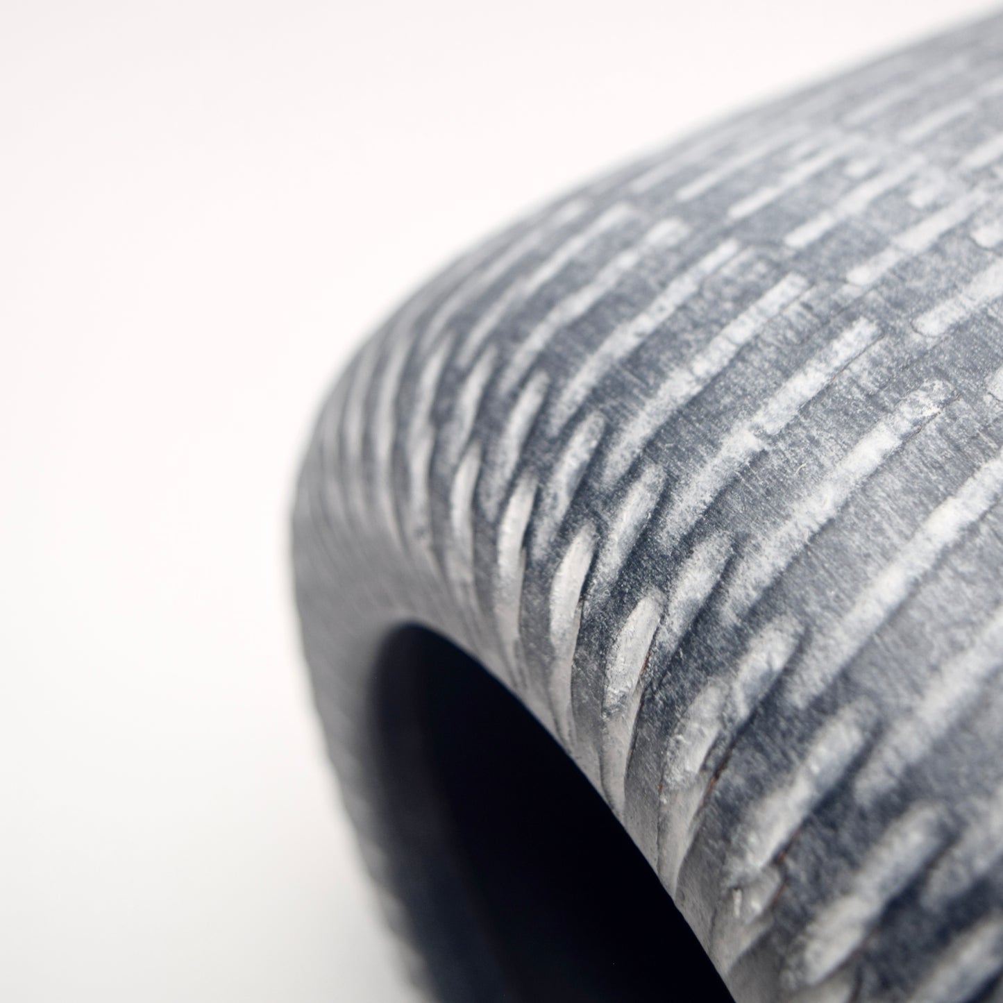 Close-up of grey terracotta vase with a linear white pattern