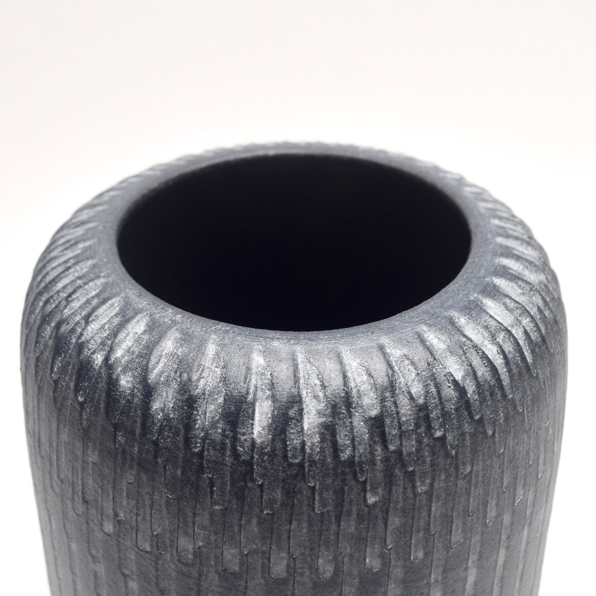 Close-up of the top of grey textured terracotta vase 