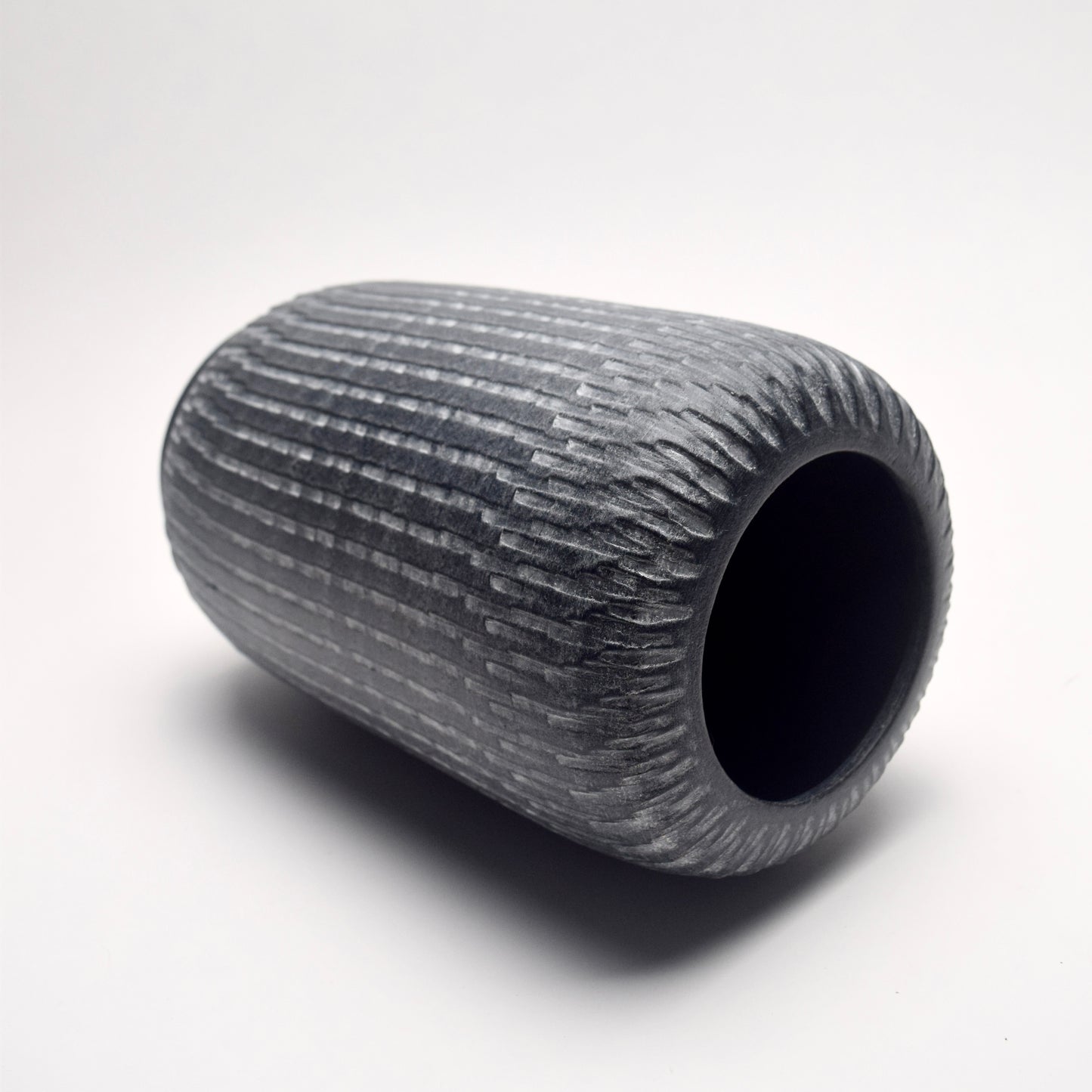 Grey Textured terracotta vase with white linear pattern, on its side