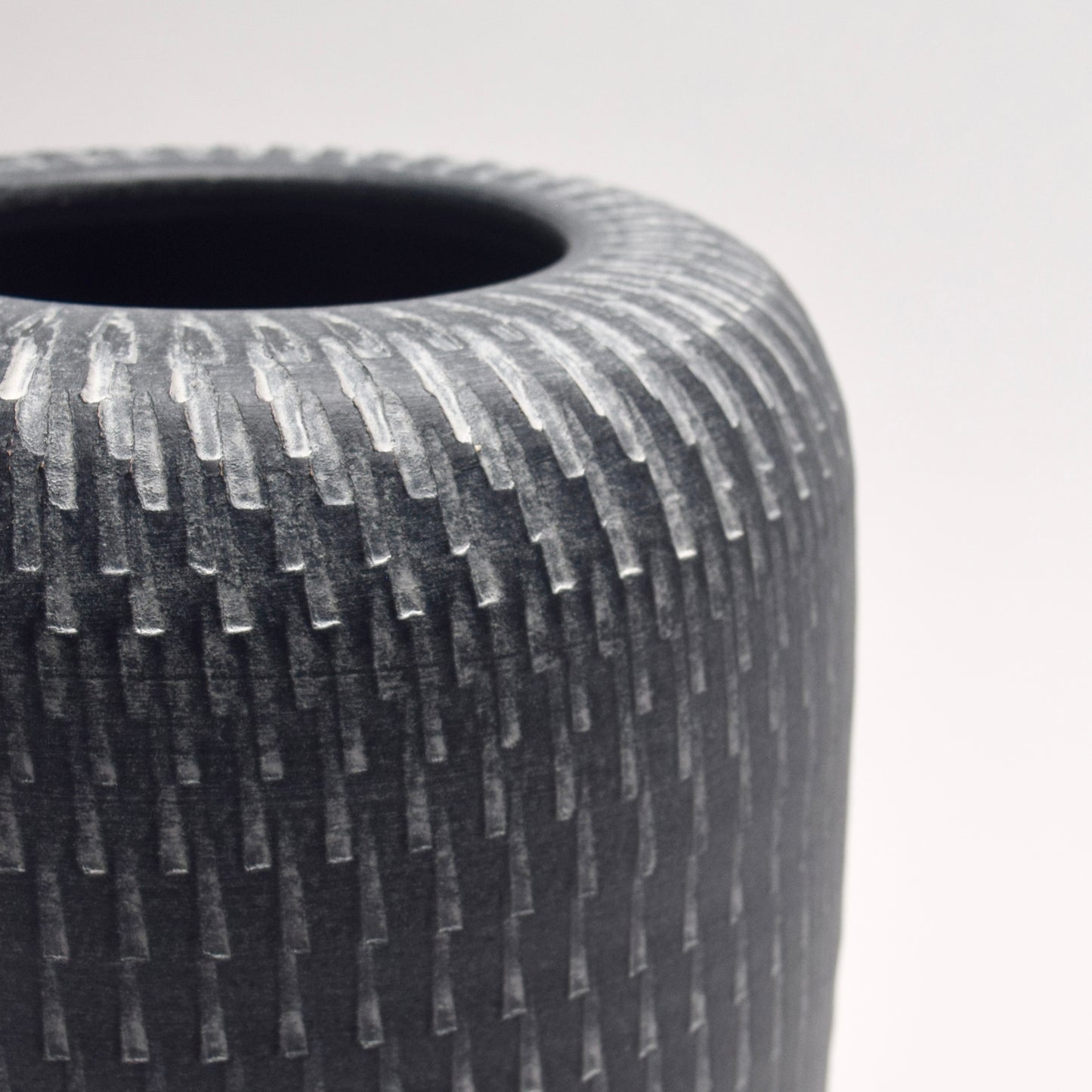 Textured grey vase with a pillar shape and linear pattern detailing