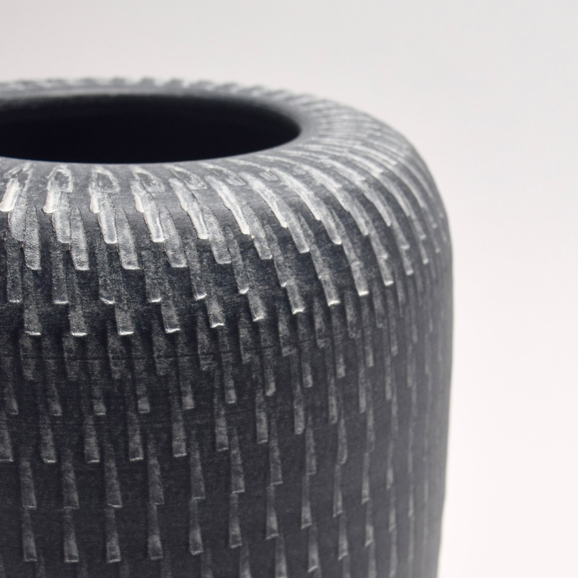 Textured grey vase with a pillar shape and linear pattern detailing
