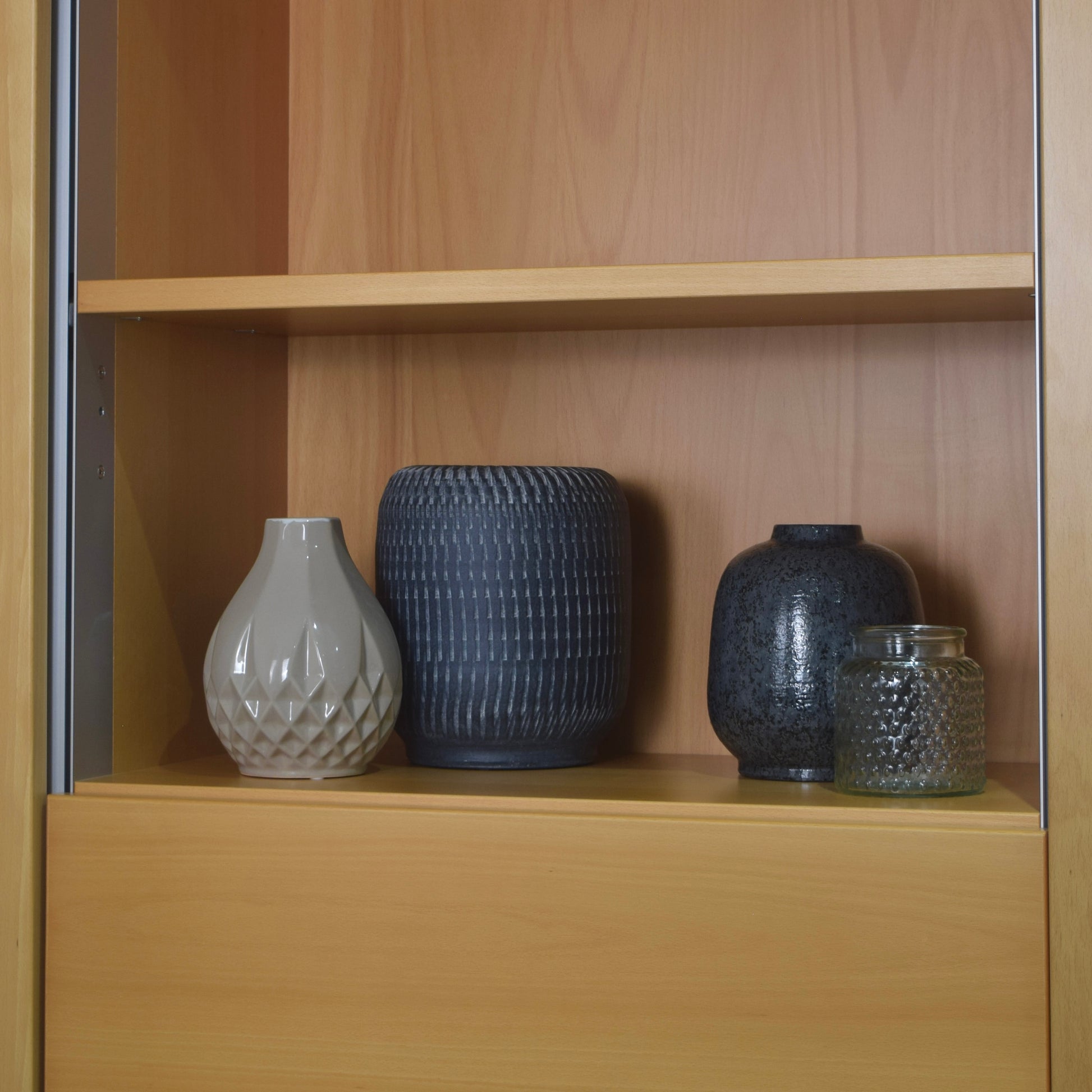 Four decorative vases on a wooden shelf