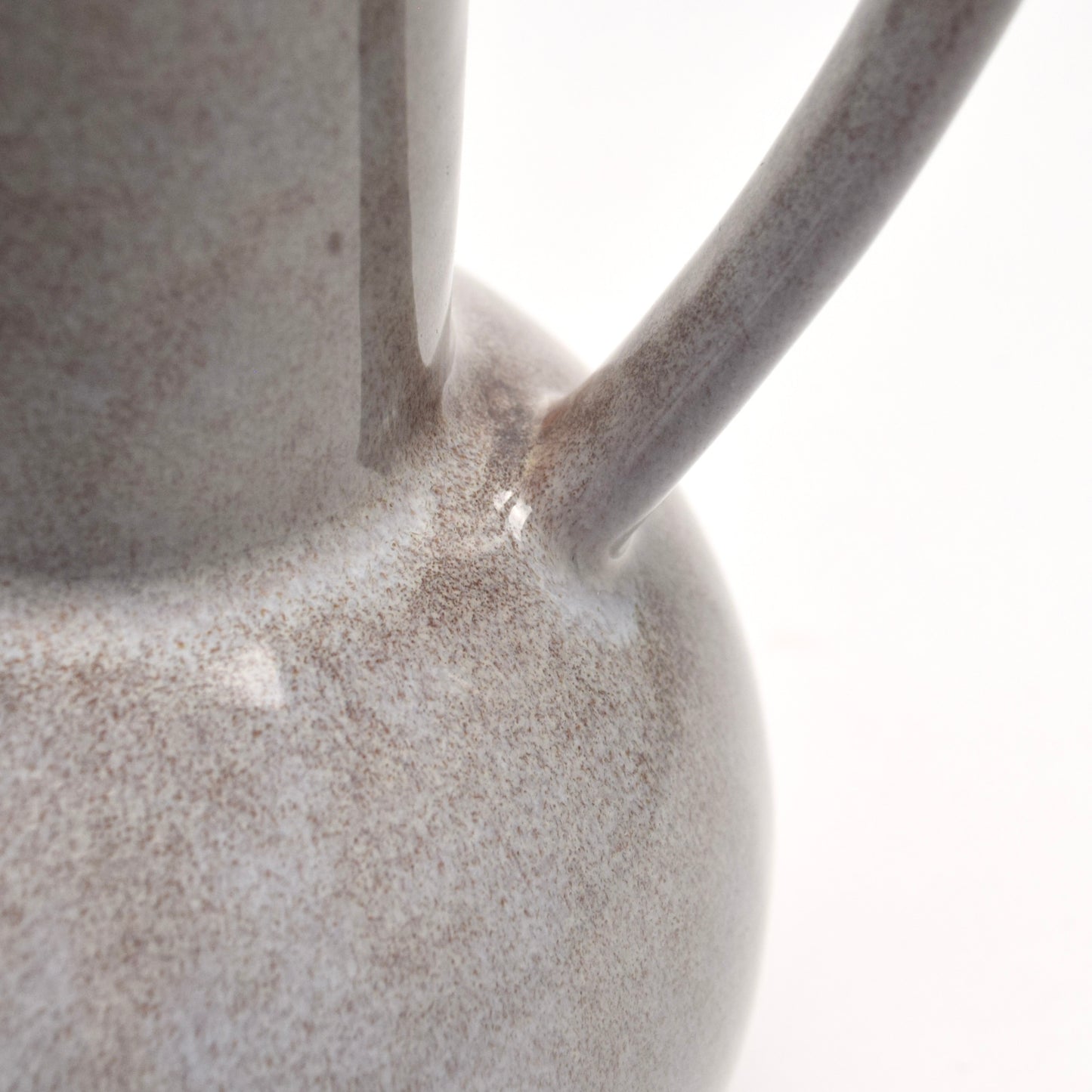 Close-up of a ceramic decorative jug with a speckled brown surface and handle.