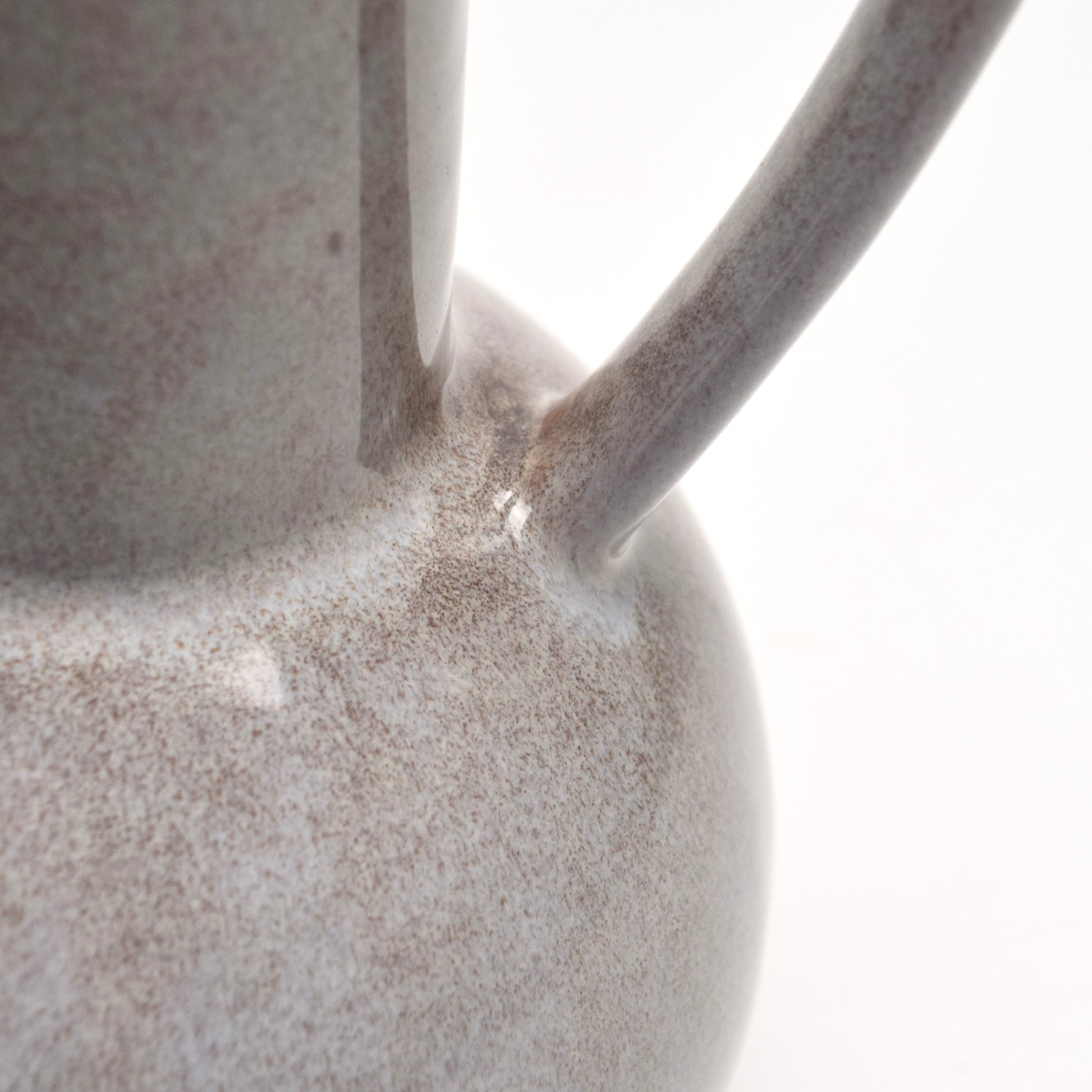 Close-up of a ceramic decorative jug with a speckled brown surface and handle.