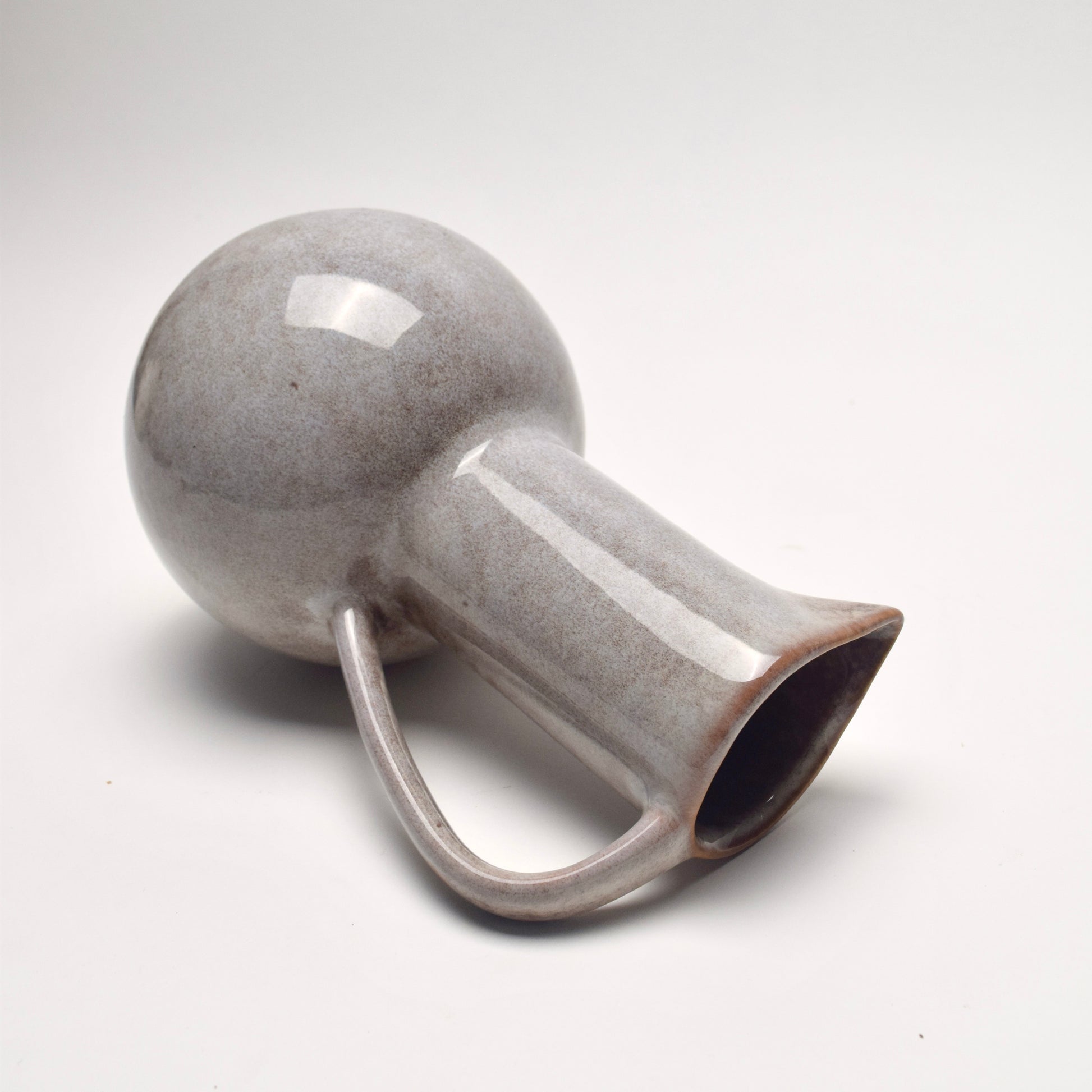 Grey ceramic glazed jug with speckled brown details, on its side