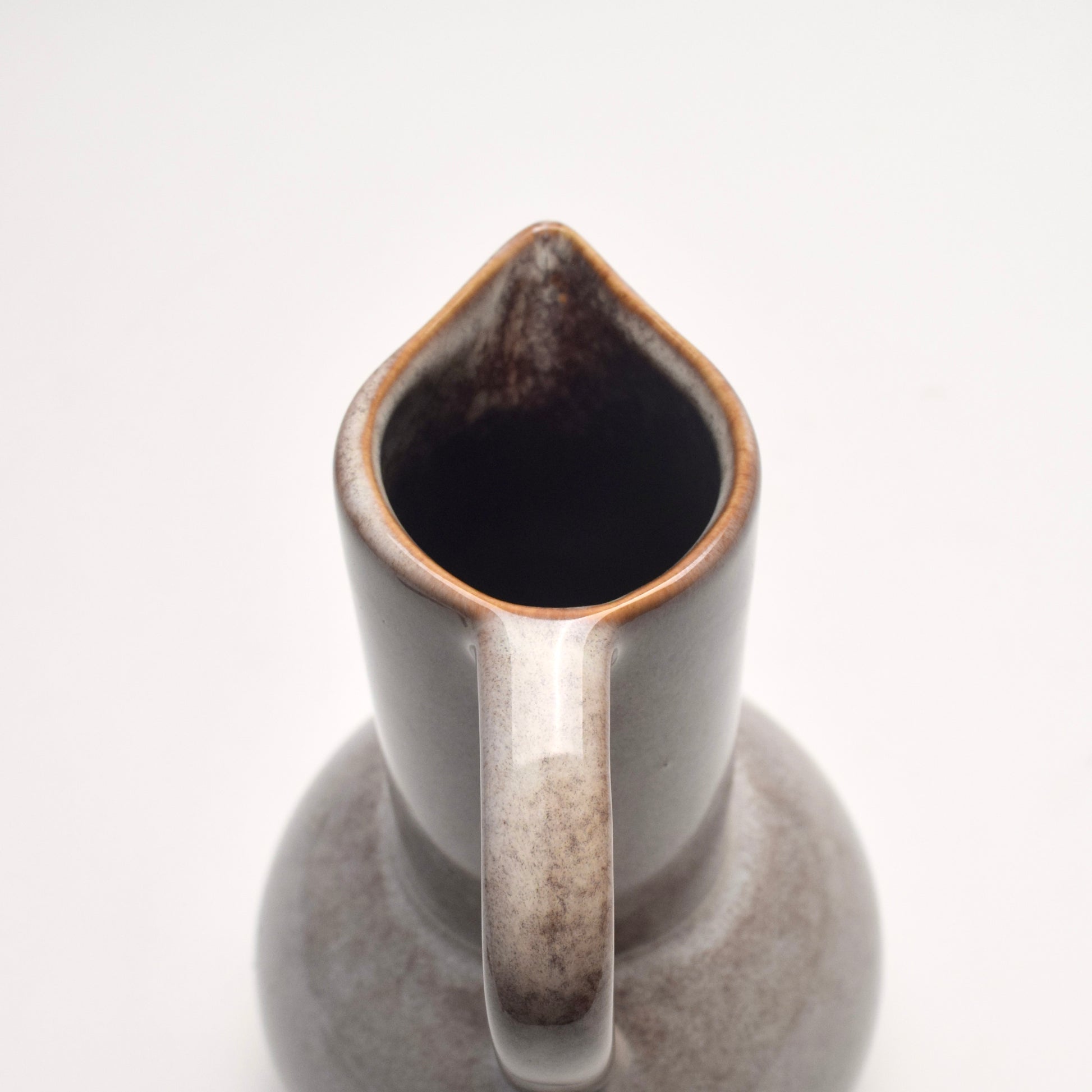 Decorative ceramic glazed jug with grey and brown speckles, view  from the top showing the handle