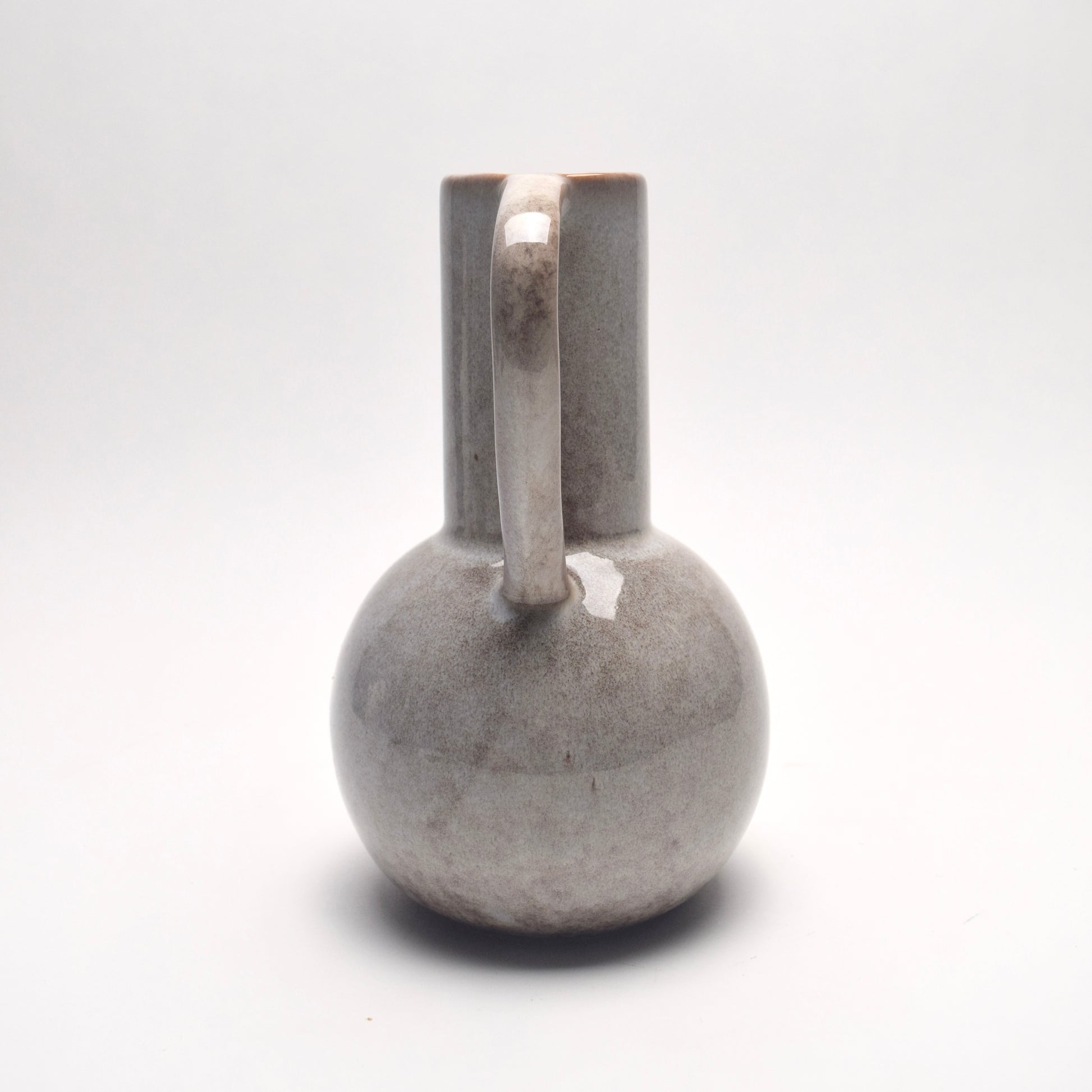 Decorative light grey ceramic glazed jug with handle view from the back