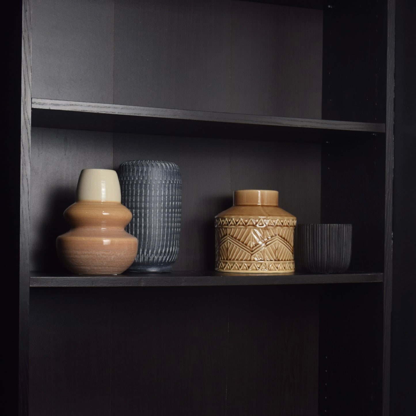 Decorative set of four vases on a dark wooden shelf