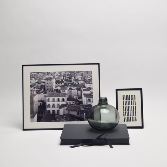 Framed black and white photo, dark vase, and framed cityscape photograph for monochrome interior styling