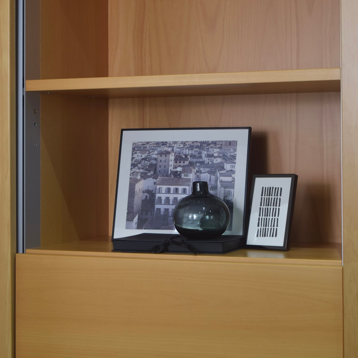 Wooden shelf with a black vase and framed picture on a wooden bookcase