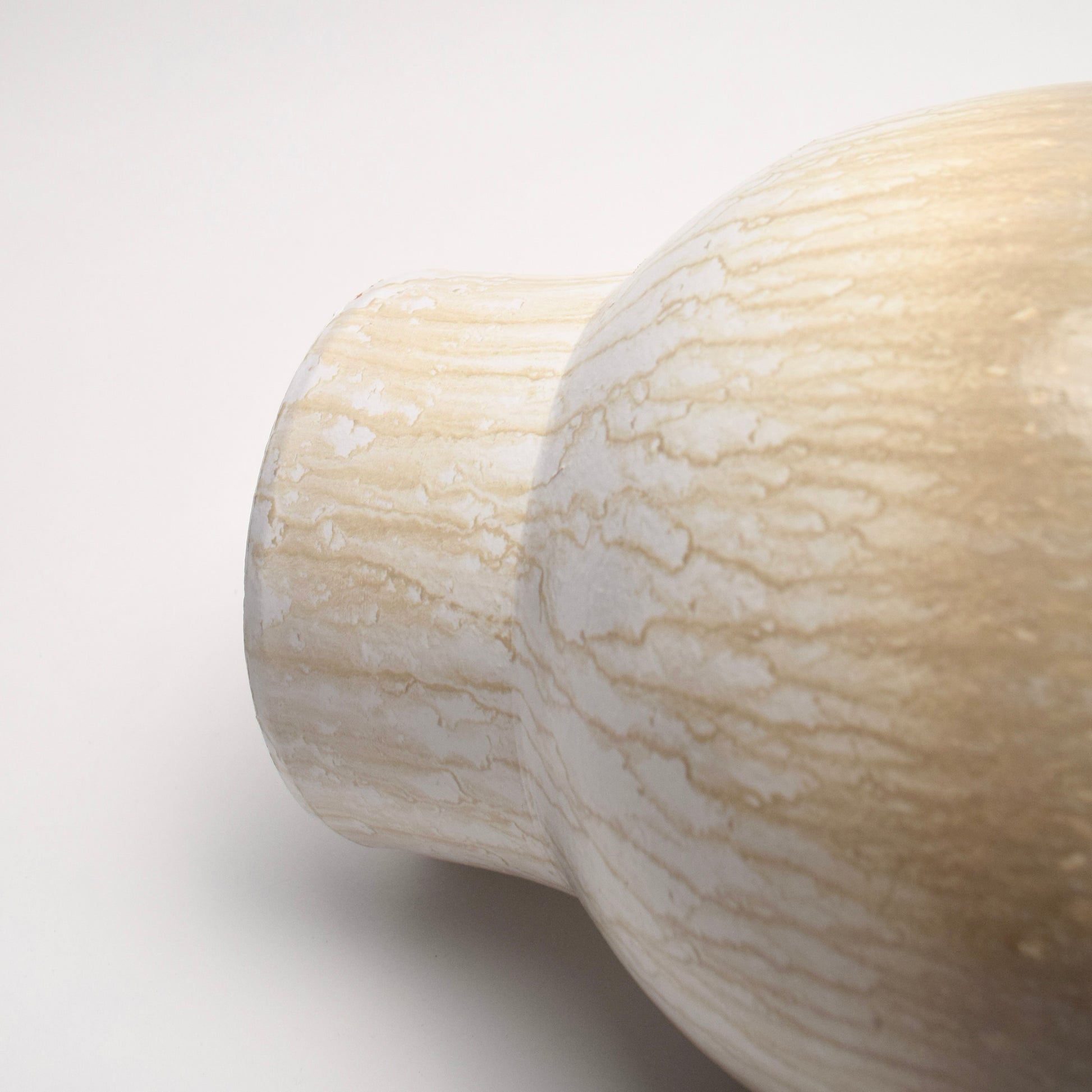 Close-up of a vase with neutral glazed drip-effect pattern on a light background