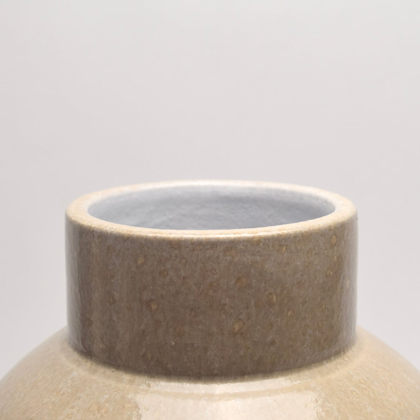 Close-up of a ceramic vase with a textured brown and beige rim 