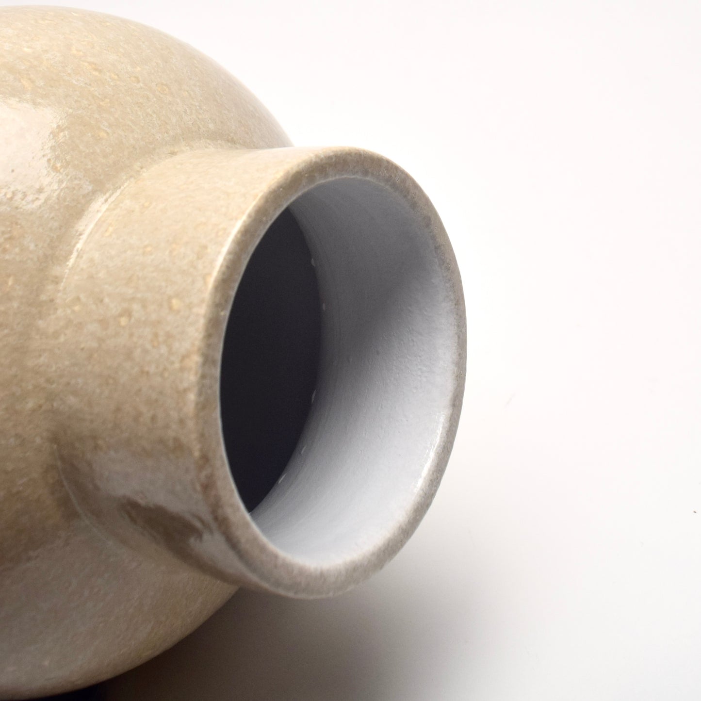 Close-up of a neutral ceramic vase with a textured surface on a white background