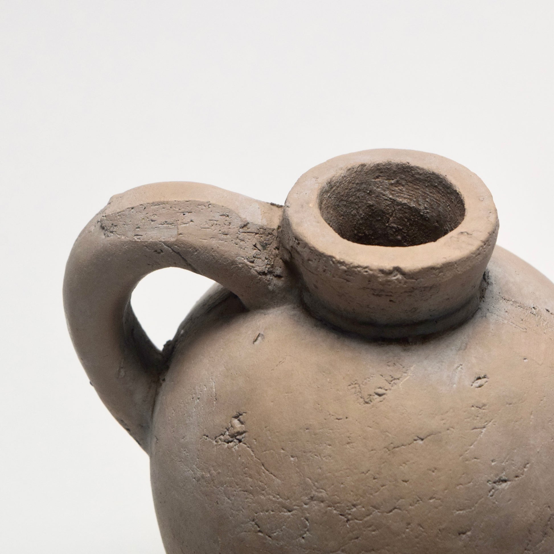 Neutral tone stone jug with small handle close up