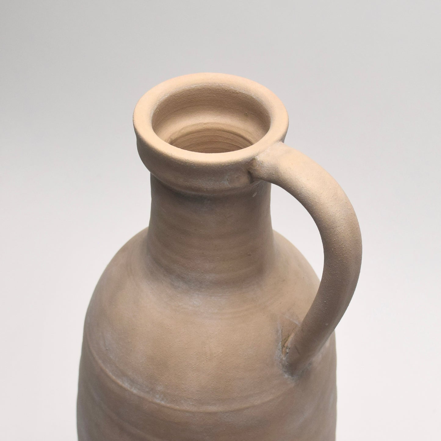 Close-up of the top of neutral stone vase with decorative handle