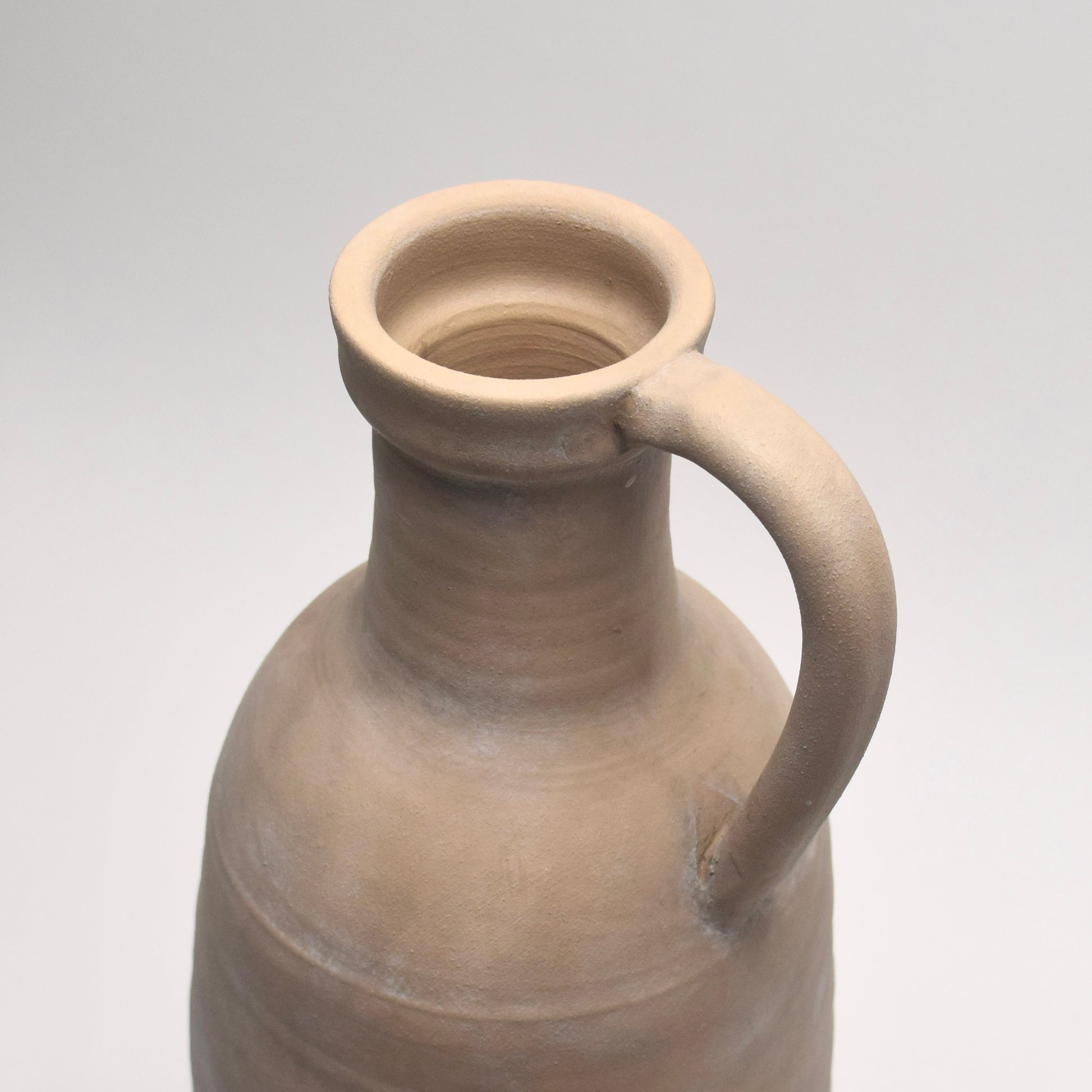 Close-up of the top of neutral stone vase with decorative handle
