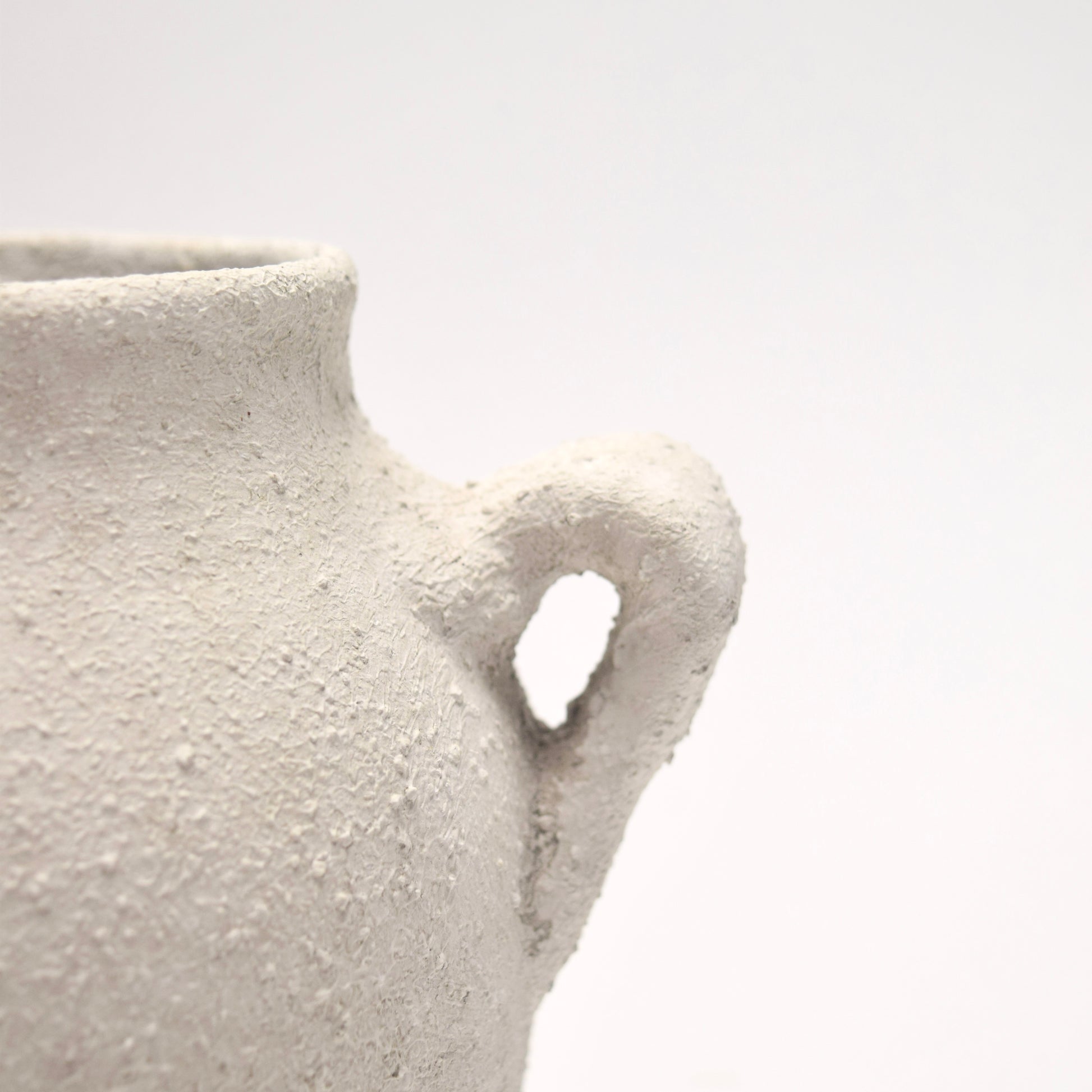 Close-up of a textured ceramic vase and its delicate handle