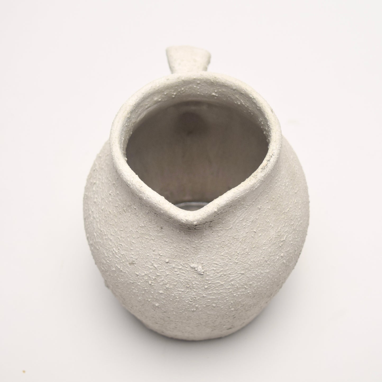 Textured ceramic vase with handle at the back on a white background