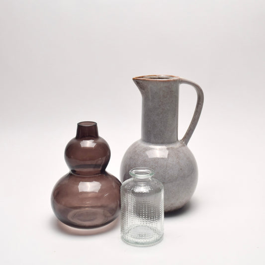 3 vases, a glass vase with a curved silhouette, a grey jug with handle and  clear dotted glass vase