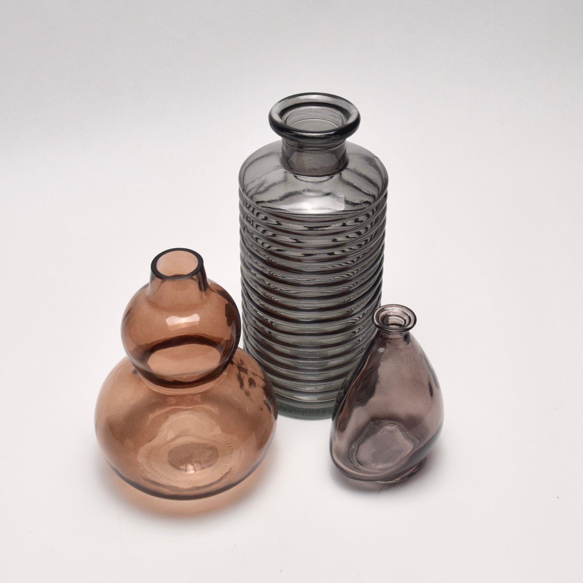 A gift set featuring three decorative glass vases in striped charcoal and earthy brown tones. 