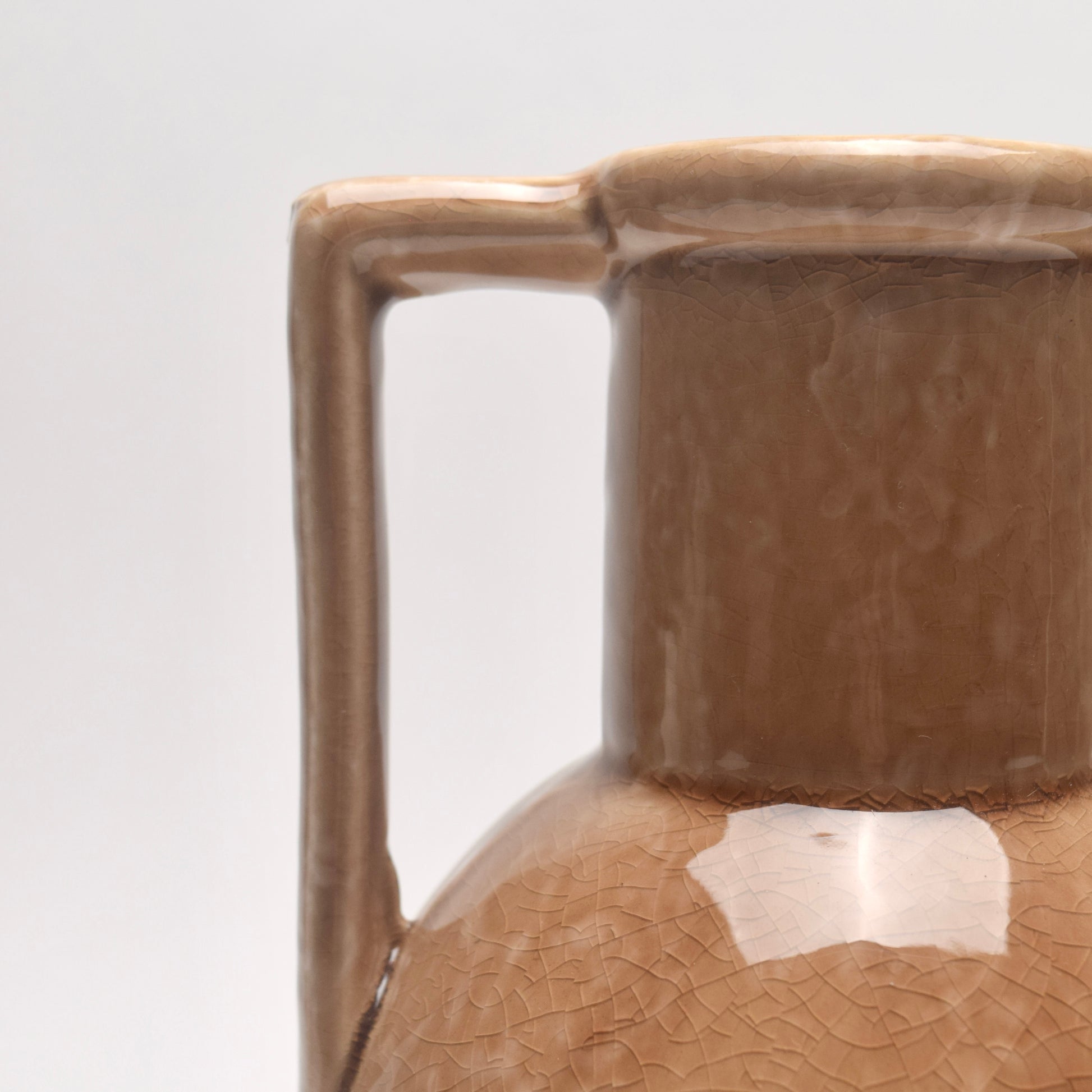 Close-up of a brown, tan, ceramic vase with bold shaped handle