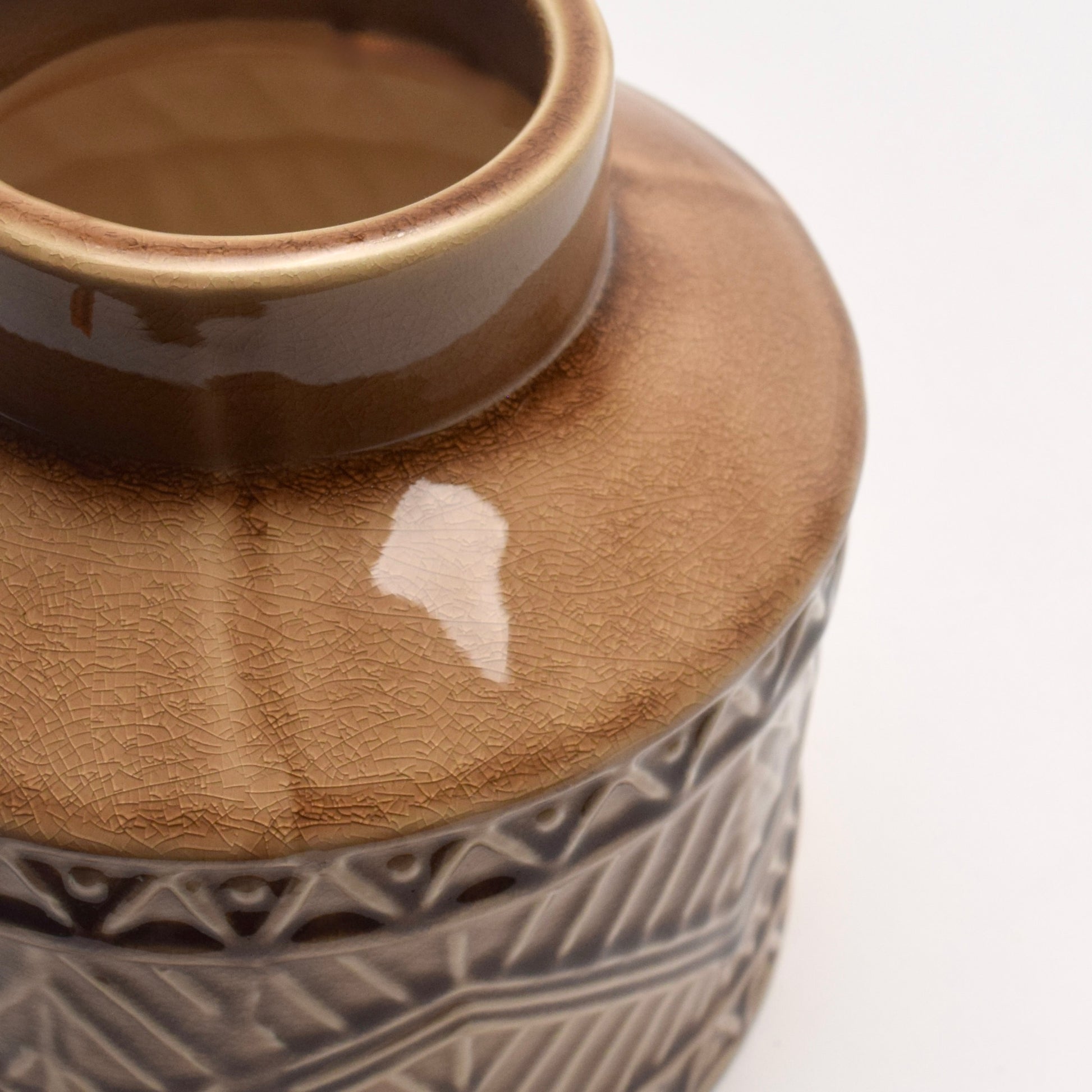 Close-up of a ceramic vase with a textured aztec pattern on its side 